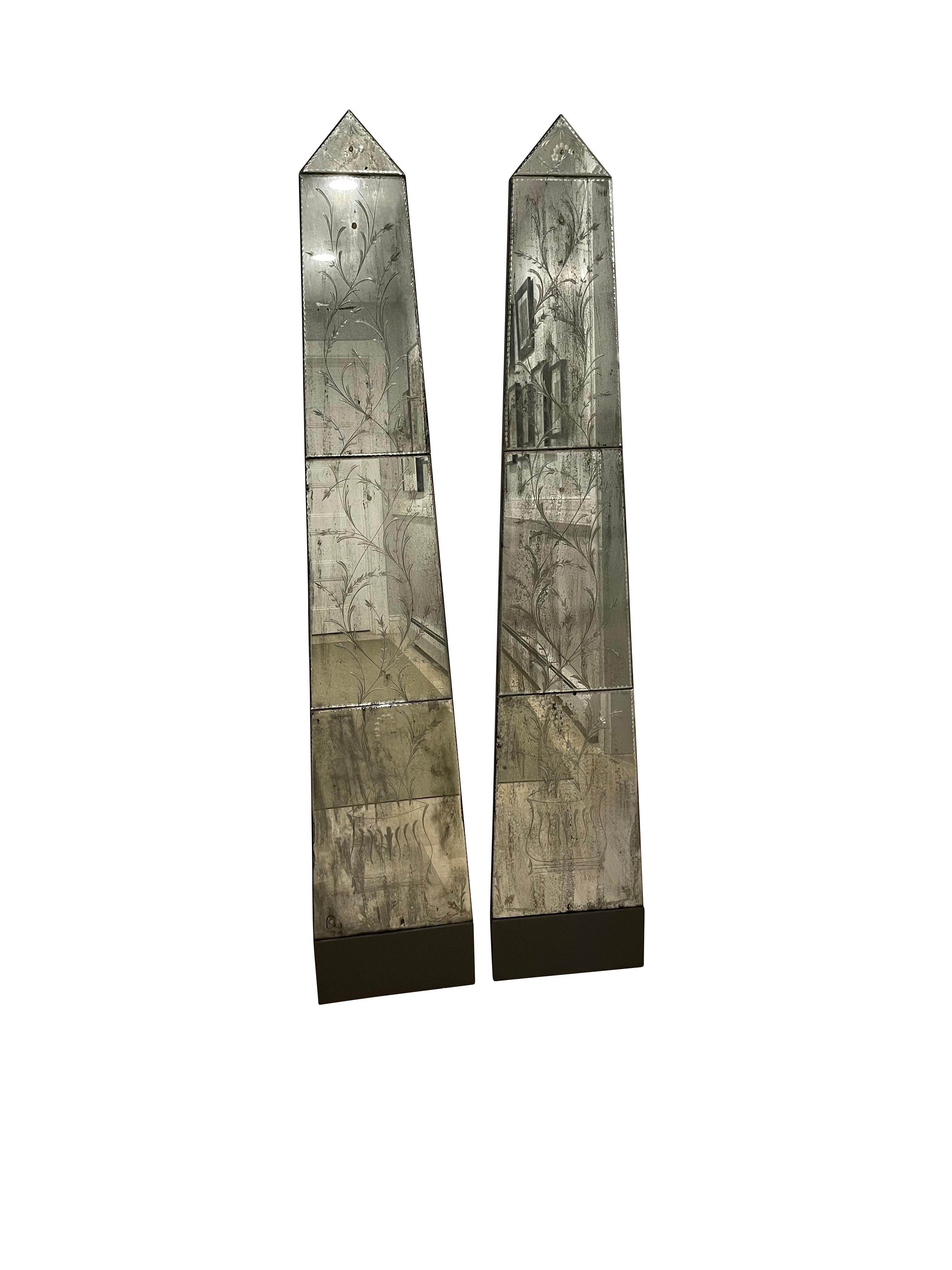Pair of Venetian obelisk form mirrored panels with botanical etchings from the 1980s. Each with multiple individual beveled panels cut and etched with botanical representations painted black panels on the reverse with proper hardware for hanging.
