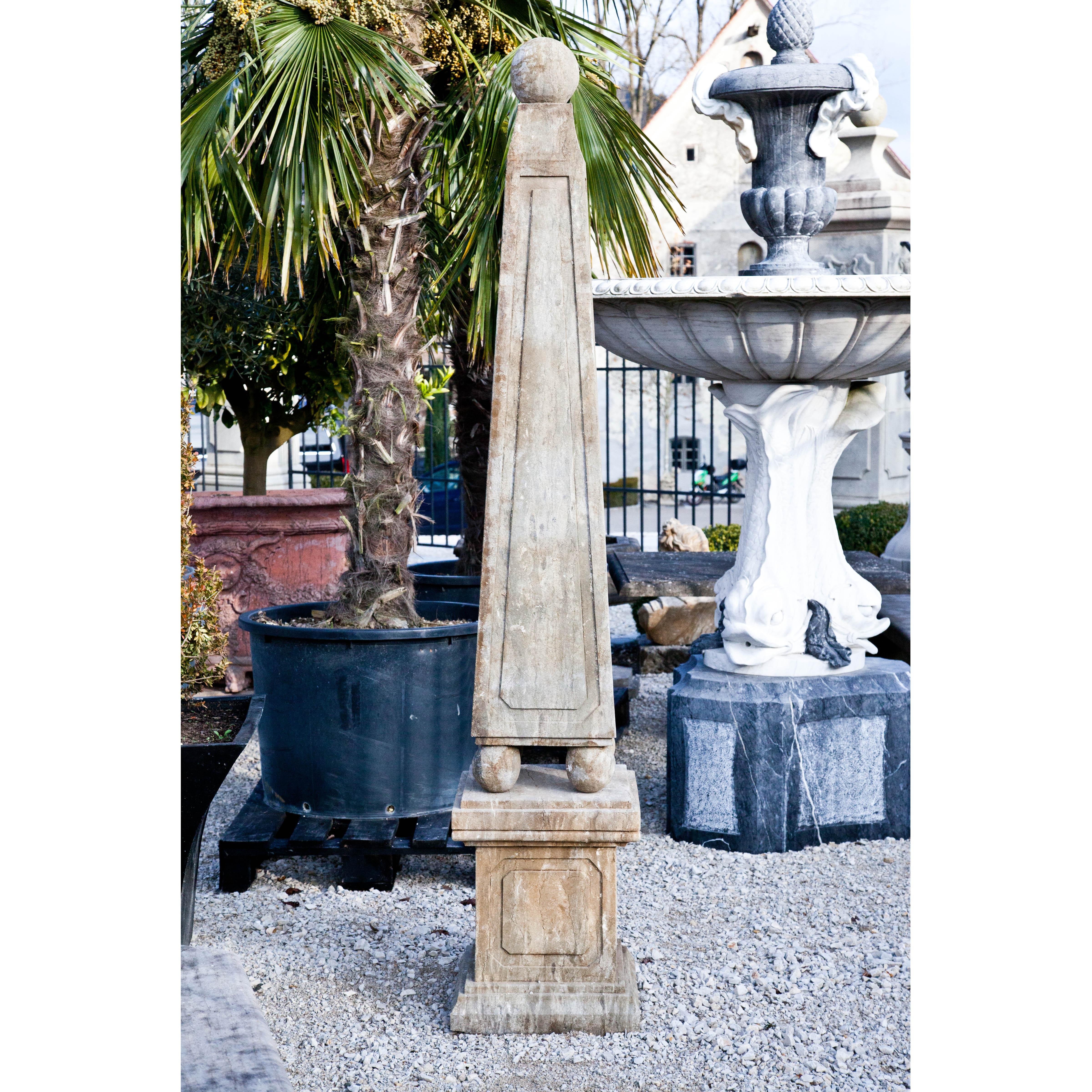 Hand carved pair of obelisks in blue stone, resting on spherical feet above a square base.