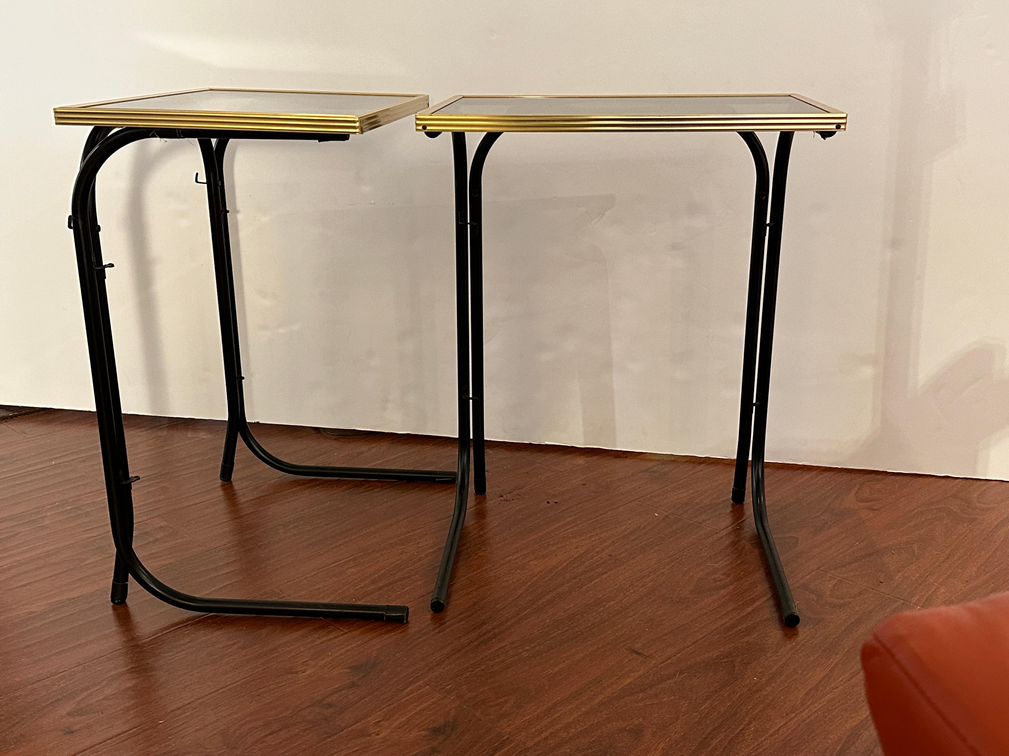 
This pair of brass and iron folding tables, combines style and functionality.  Each table features a tempered glass top framed by a sleek brass border, showcasing a clean three-line minimalist design. The folding feature adds to their