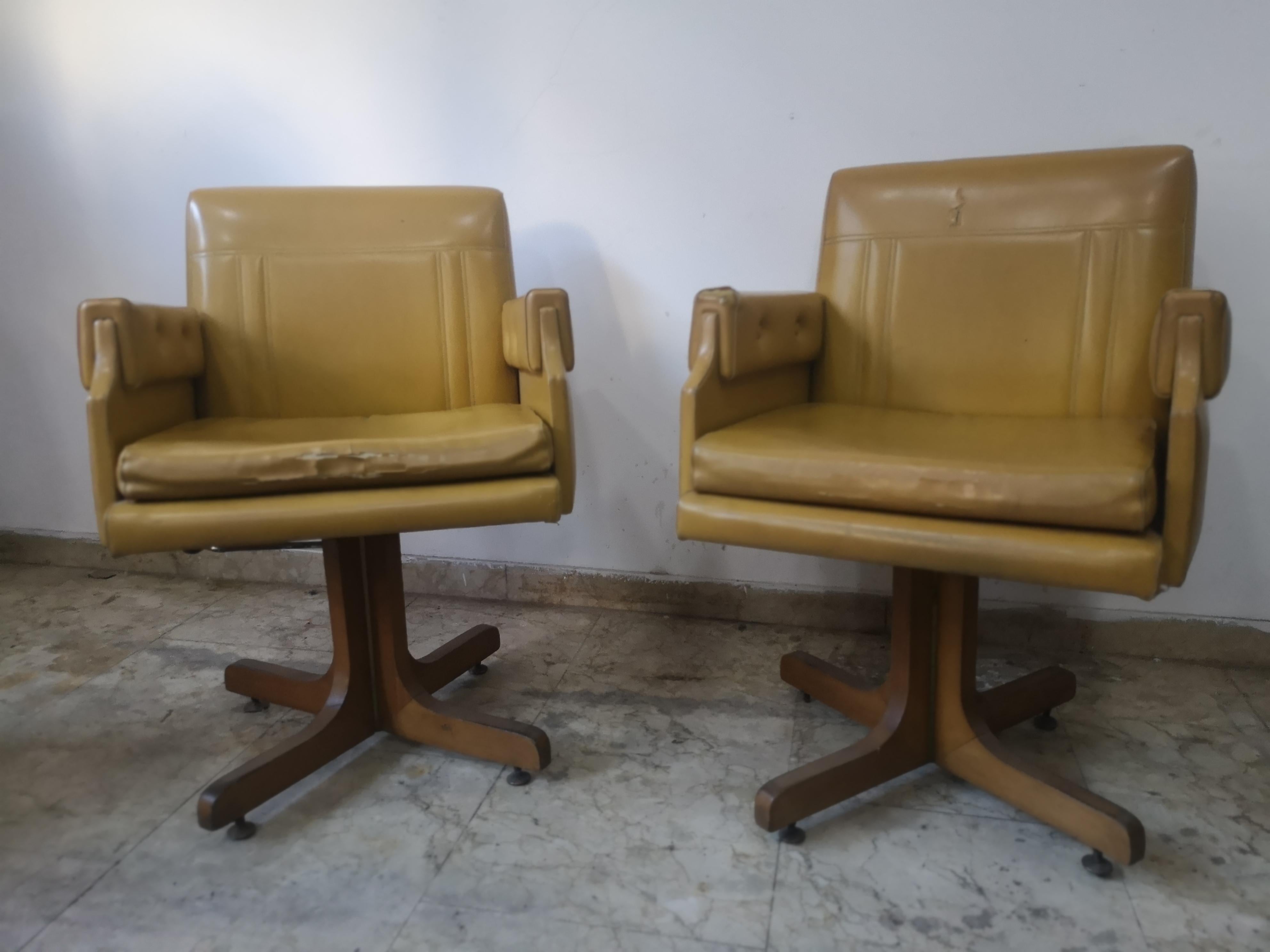 Paire de fauteuils pivotants en skaï jaune ocre des années 70
Les fauteuils ont une structure en noyer et des pieds en laiton
et un levier pour empêcher les chaises de tourner.

État des fauteuils compatible avec l'usure du temps
comme indiqué sur
