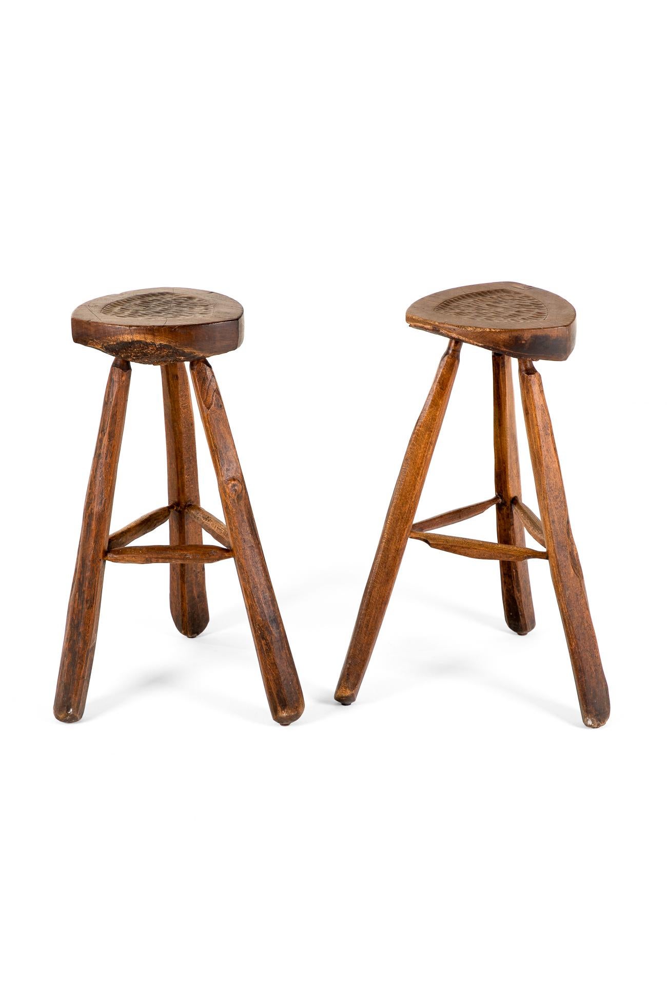 A superb Brutalist pair of mid-century oak bar stools.

The angular and uneven seat tops of each of the two stools is hewn out of a single piece of thick timber with smooth tops with gentle pitted inlay detailing to each.

Underneath each seat the