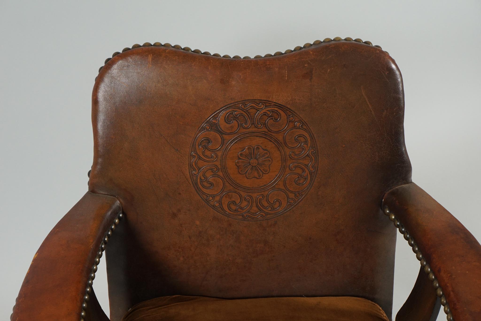 Pair of Arts & Crafts armchairs with leather covered arms and back, with large brass studs.
The chairs are in oak with carved rondel on the front legs the leather of the inside backrest
has an impressed floral stamp with a center stylized rose.