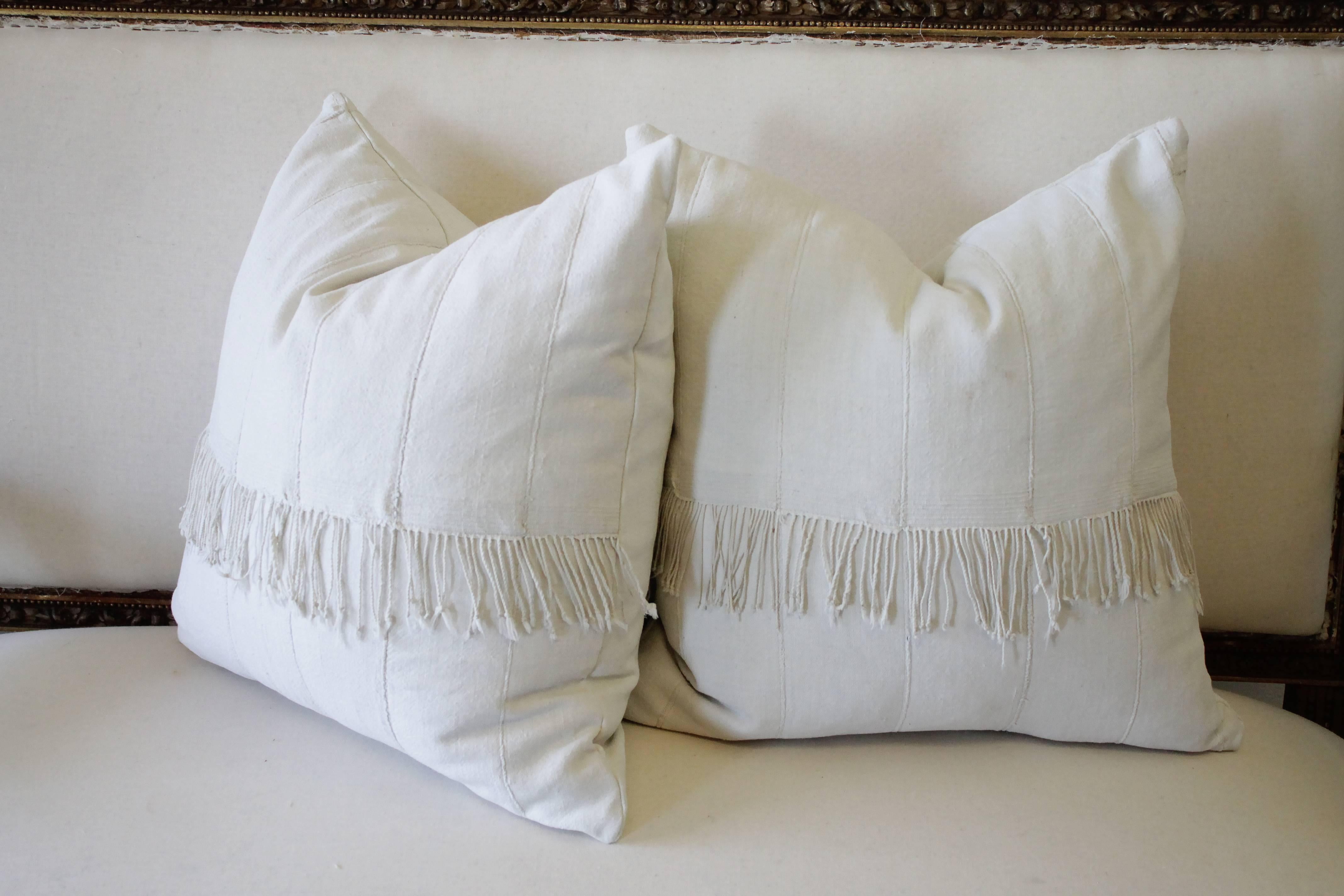 Pair of creamy white African mudcloth pillows with original fringe accents
off-white color, thick nubby soft to the touch, these original stitched seams and original fringe accents were kept to make these beautiful pillows.
Hidden zipper closure,