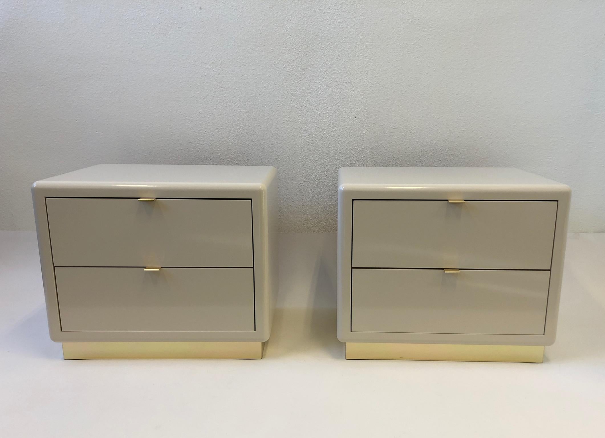 A glamorous 1980s pair of two drawer nightstands by Steve Chase. The nightstands are constructed of wood that’s off white polished lacquered, the pulls and the base are brass. 

Dimensions: 24” wide 18” deep 20” high.