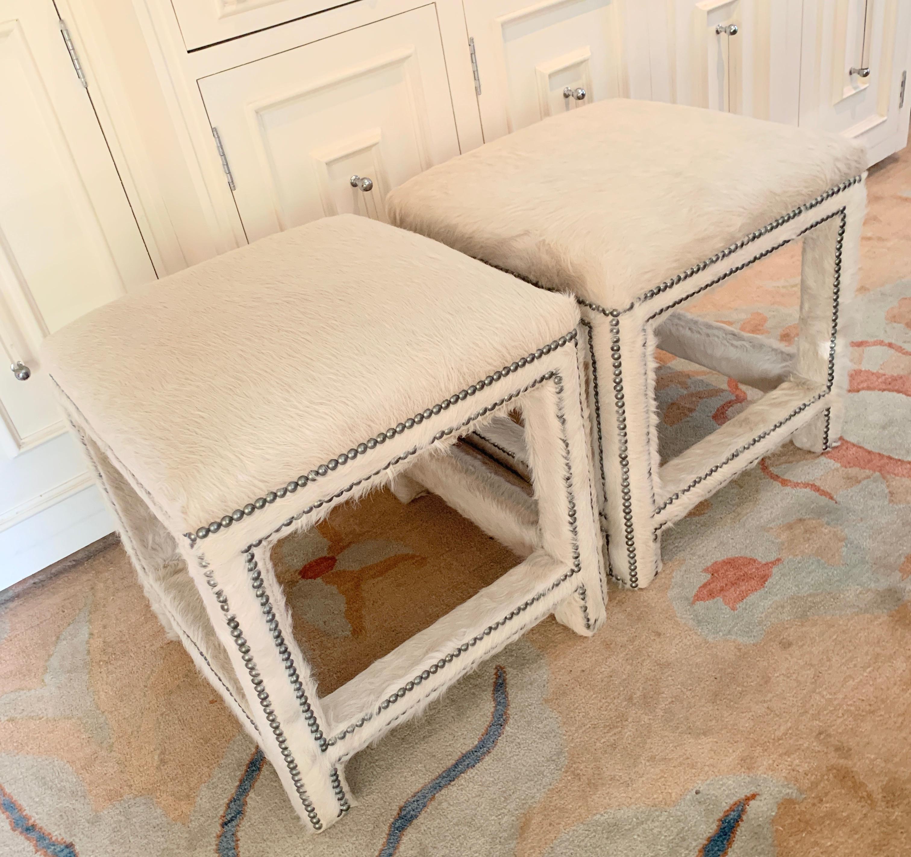 Pair of off- white pony skin benches, ottomans or stools -

The square wood frame benches are completely upholstered in off white pony skin / cow hide. Nail heads accents throughout give the benches a very clean and classic, yet modern look. A