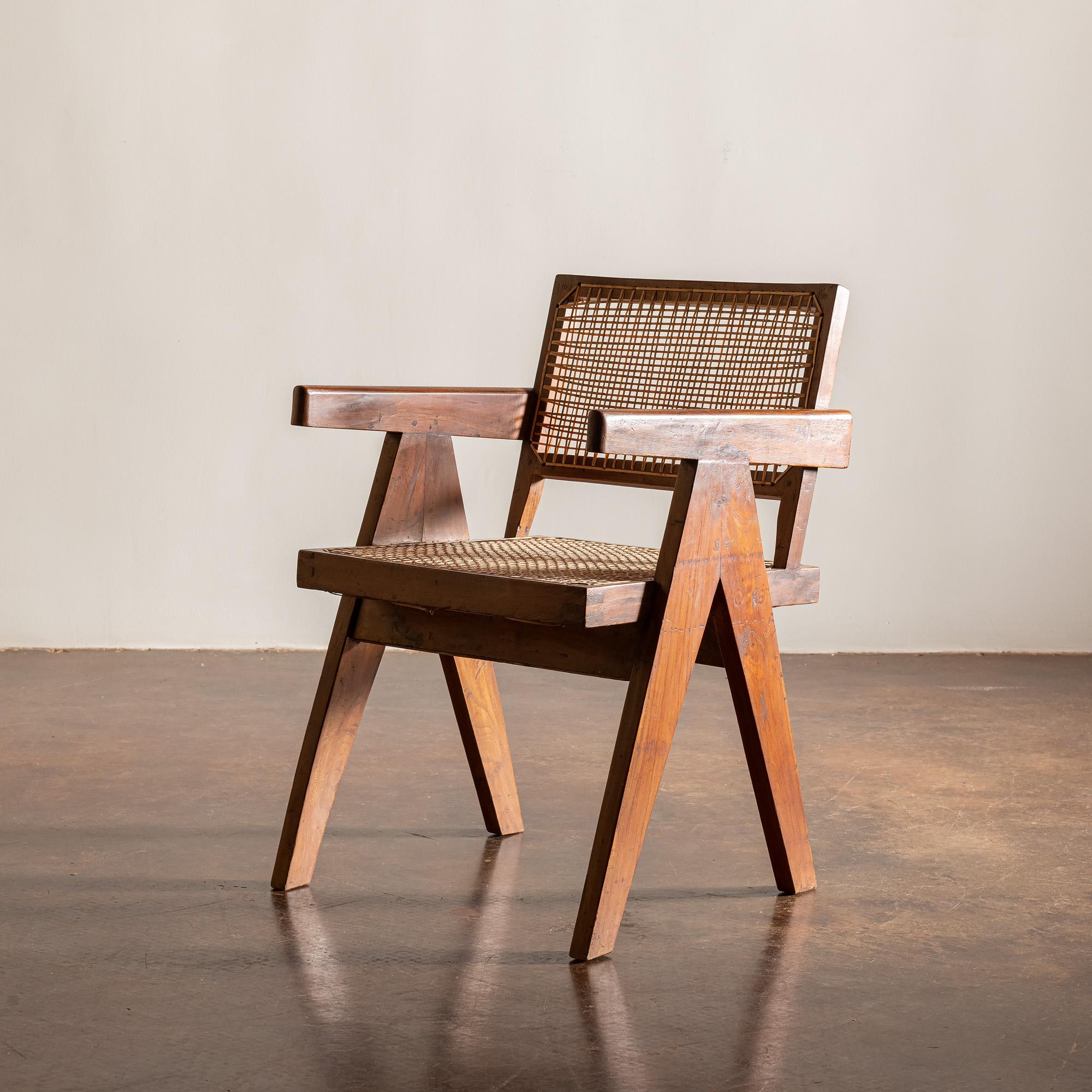 A pair of iconic office armchairs designed by Pierre Jeanneret for Chandigarh, India. Teak and cane, 1950s.  

One of these examples has original lettering on the seat back as can be seen in the 5th image.  These chairs come with custom seat