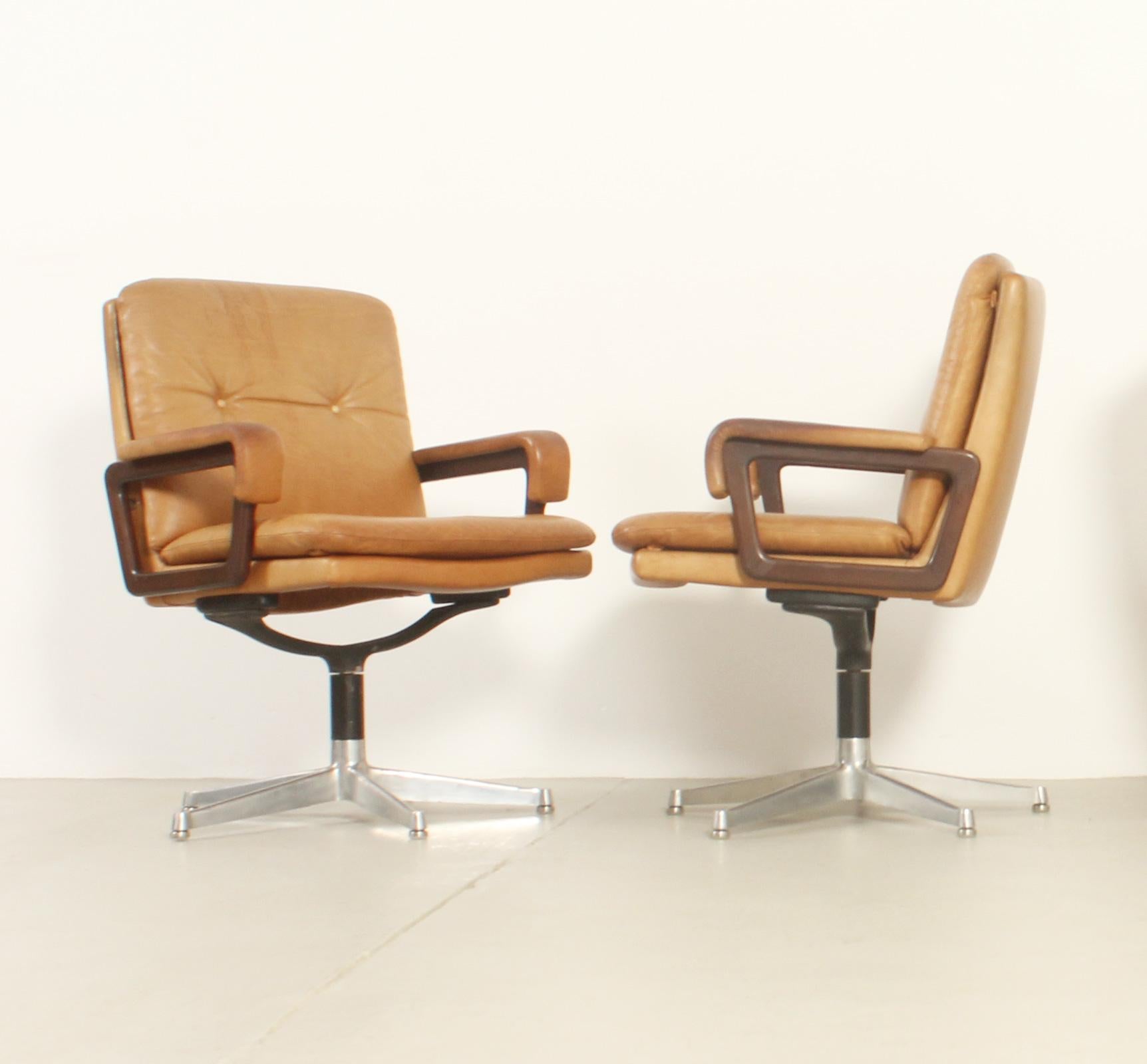 Pareja de sillones de oficina diseñados por André Vandenbeuck en la década de 1960 y fabricados por Arflex, Italia. Rara versión de escritorio giratorio en piel color canela original, brazos de madera y bases de acero pulido.