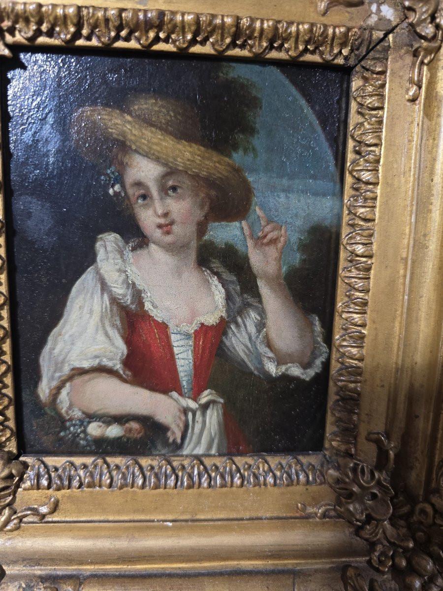Charmante paire de peintures à l'huile sur panneaux de bois représentant deux jeunes bergères dans un paysage bucolique. Chaque personnage, habillé à la mode campagnarde du XIXe siècle et coiffé d'un chapeau de paille, incarne la douceur et