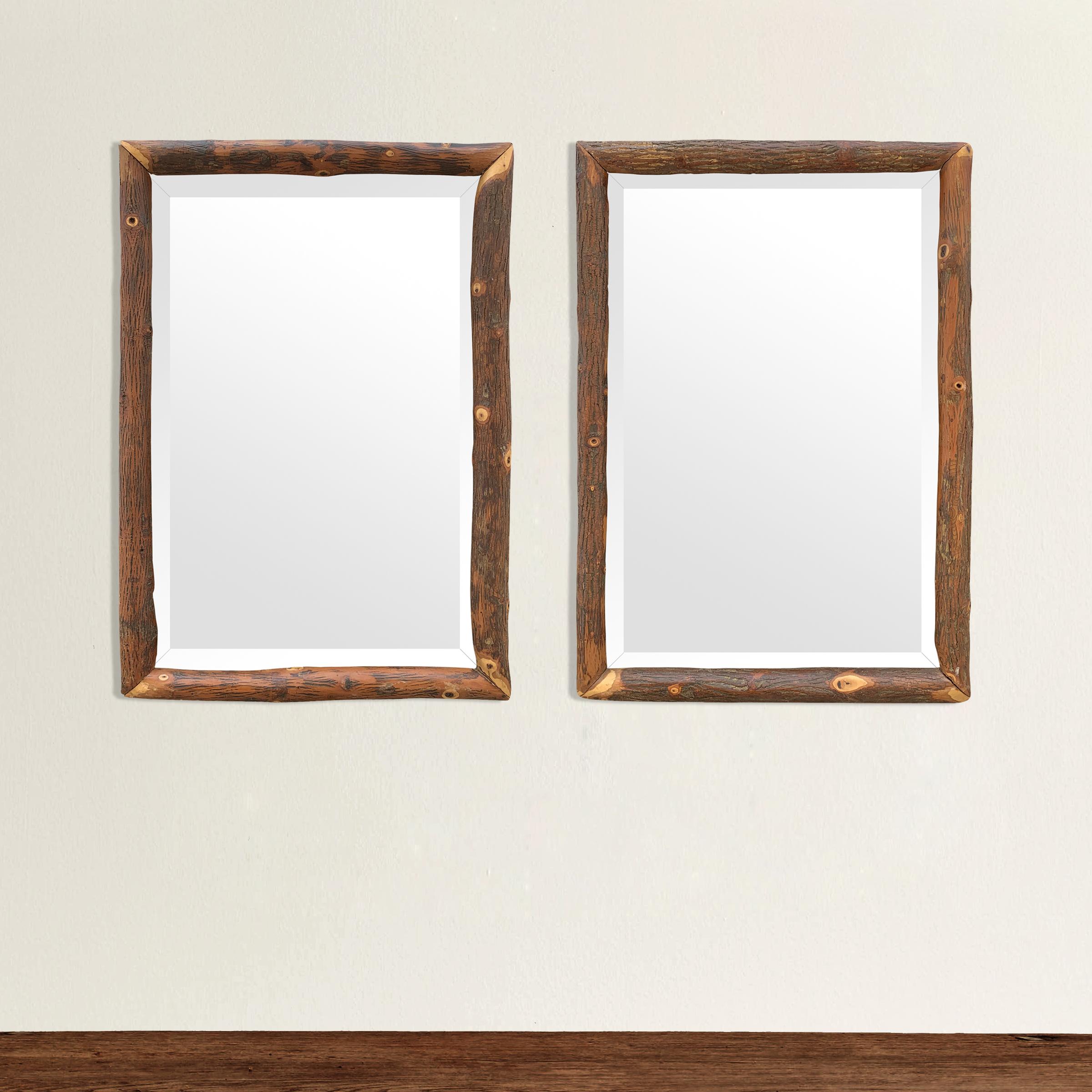 A wonderful and playful pair of mid-20th century American Old Hickory framed beveled mirrors, with the frames being made from hickory tree trunks and retaining their beautiful figural bark.