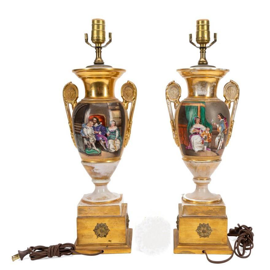 Pareja de urnas francesas de porcelana Old Paris, ahora montadas como lámparas, S. XIX, cada una con una escena doméstica figurada que representa a un caballero, posiblemente Carlos I y su familia, y una escena paisajística de reserva, sobre zócalo
