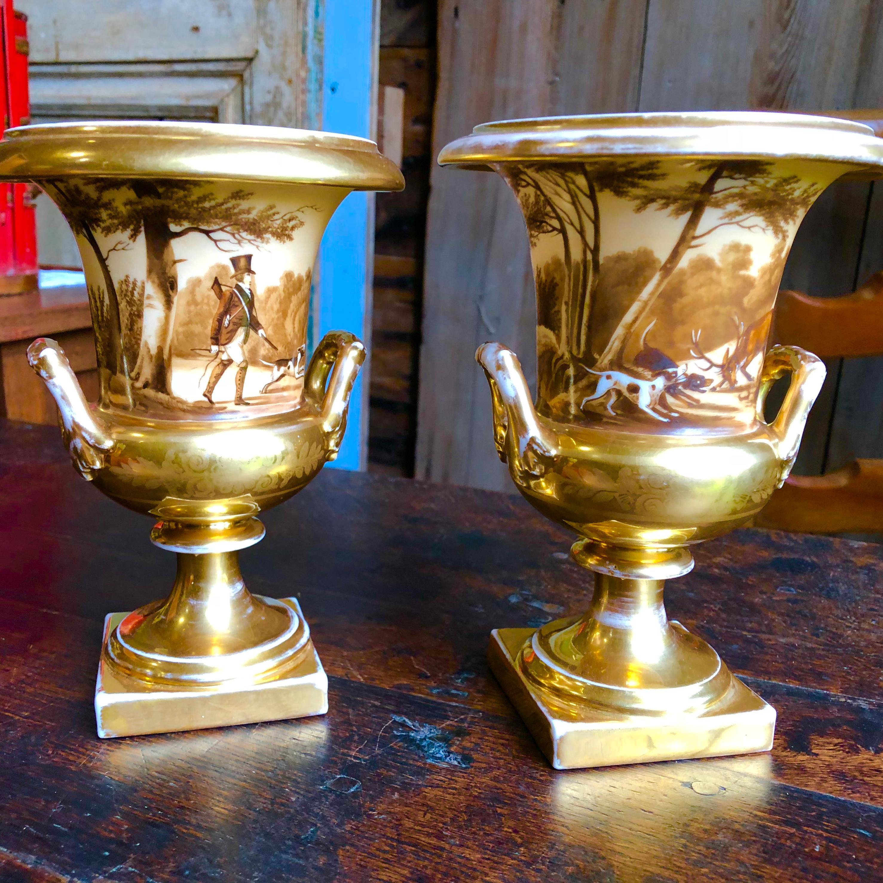 A charming pair of Old Paris porcelain Medici-form vases, with painted hunting theme decoration with gilded details.