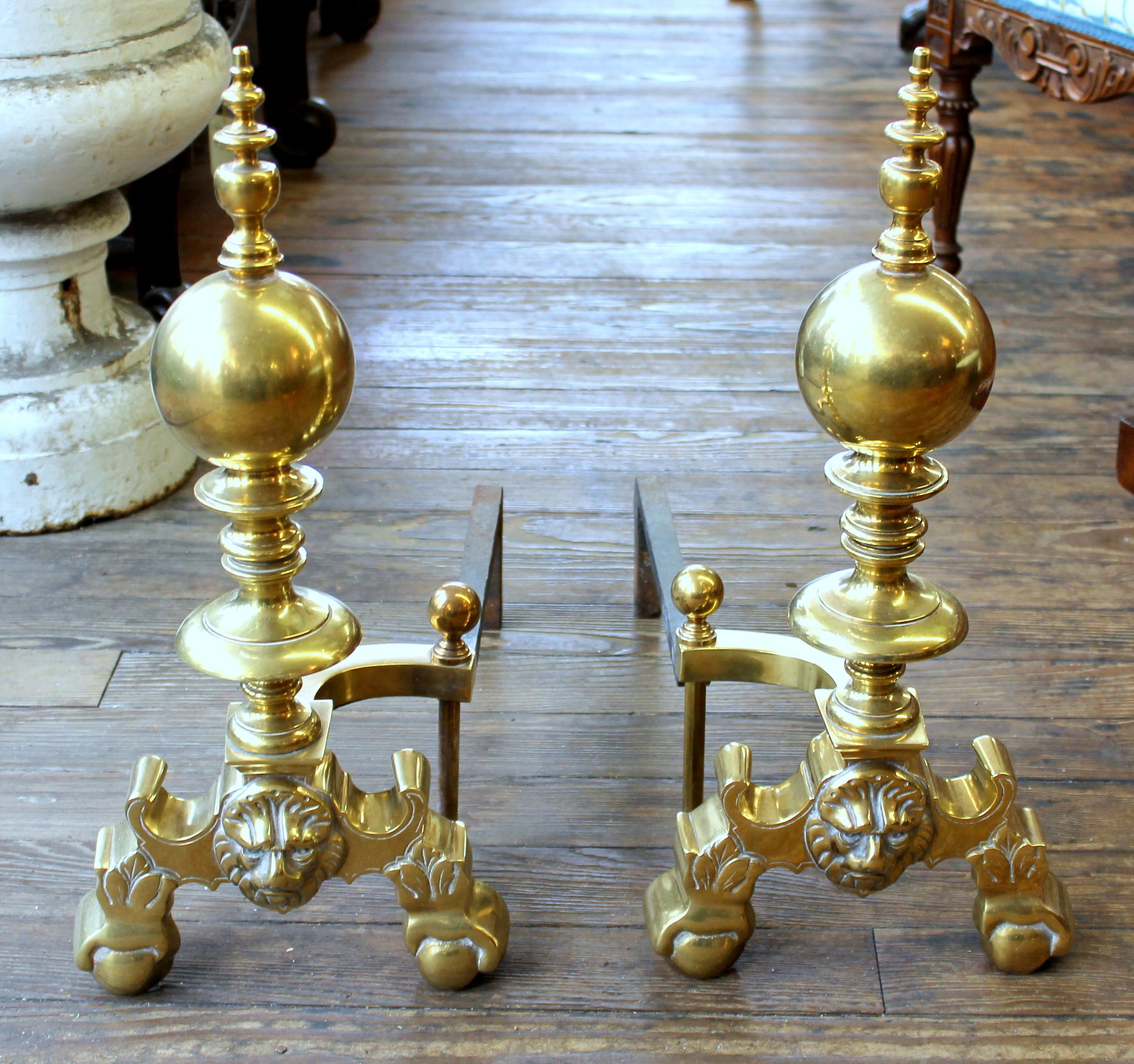 Pair of heavy solid cast brass Federal style continental lion's head andirons with cast iron returns (some wear noted and as illustrated).
   