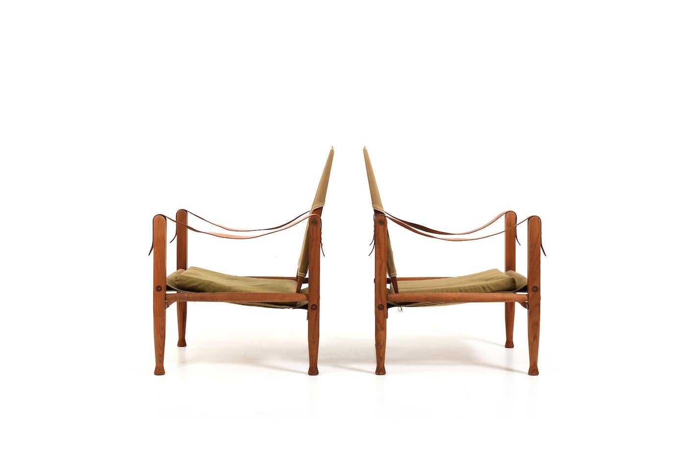 Ein Paar alte Safari-Stühle von Kaare Klint für Rud. Rasmussen Dänemark. Entworfen 1933, hergestellt in den. 1960s. Hergestellt aus massiver Eiche oder Esche. Mit originalen Lederarmlehnen, grünem Leinenstoff und Kissen. Unberührbarer Zustand, mit