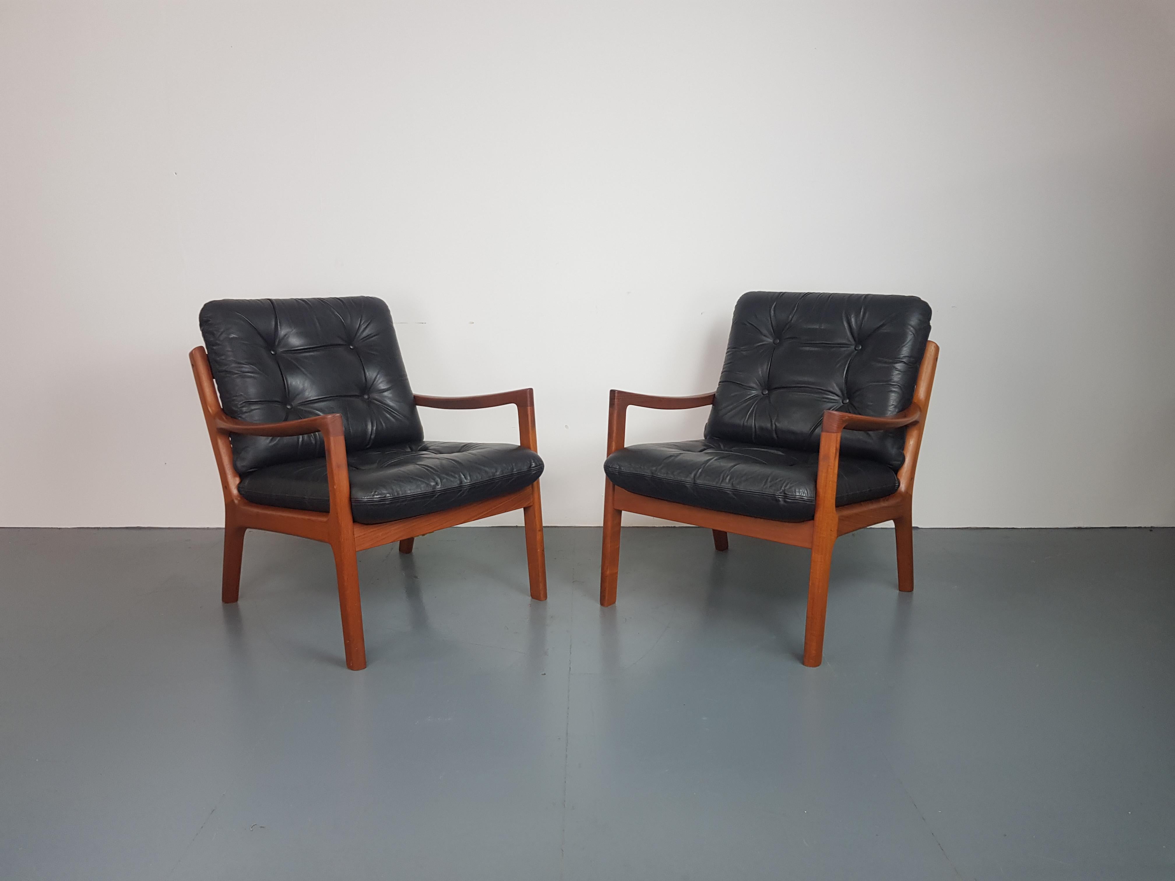 Pair of 1960s teak lounge chairs designed by Ole Wanscher for Cado.  Solid teak, with beautifully designed curved arms.  With 2 thick black leather cushions, making the chair supremely comfortable.
Approx dimensions:

Width 69 cm

Height 79