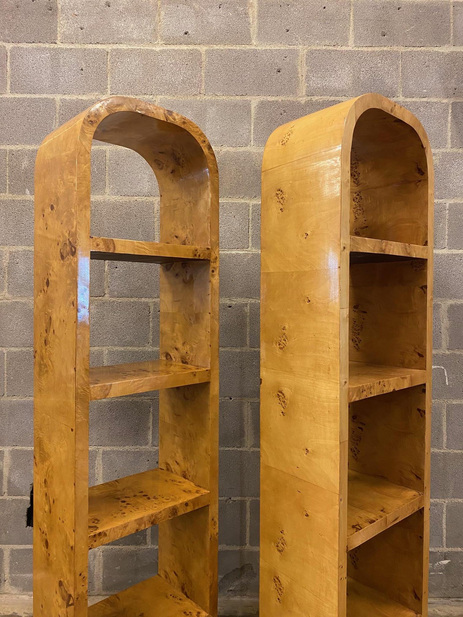 Pair of matched olive burl arched etageres.  Fixed shelf units rest on solid plinth bases.  Decorative black turned risers elevate the case and allow the pieces to visually float.  USA, 1970's