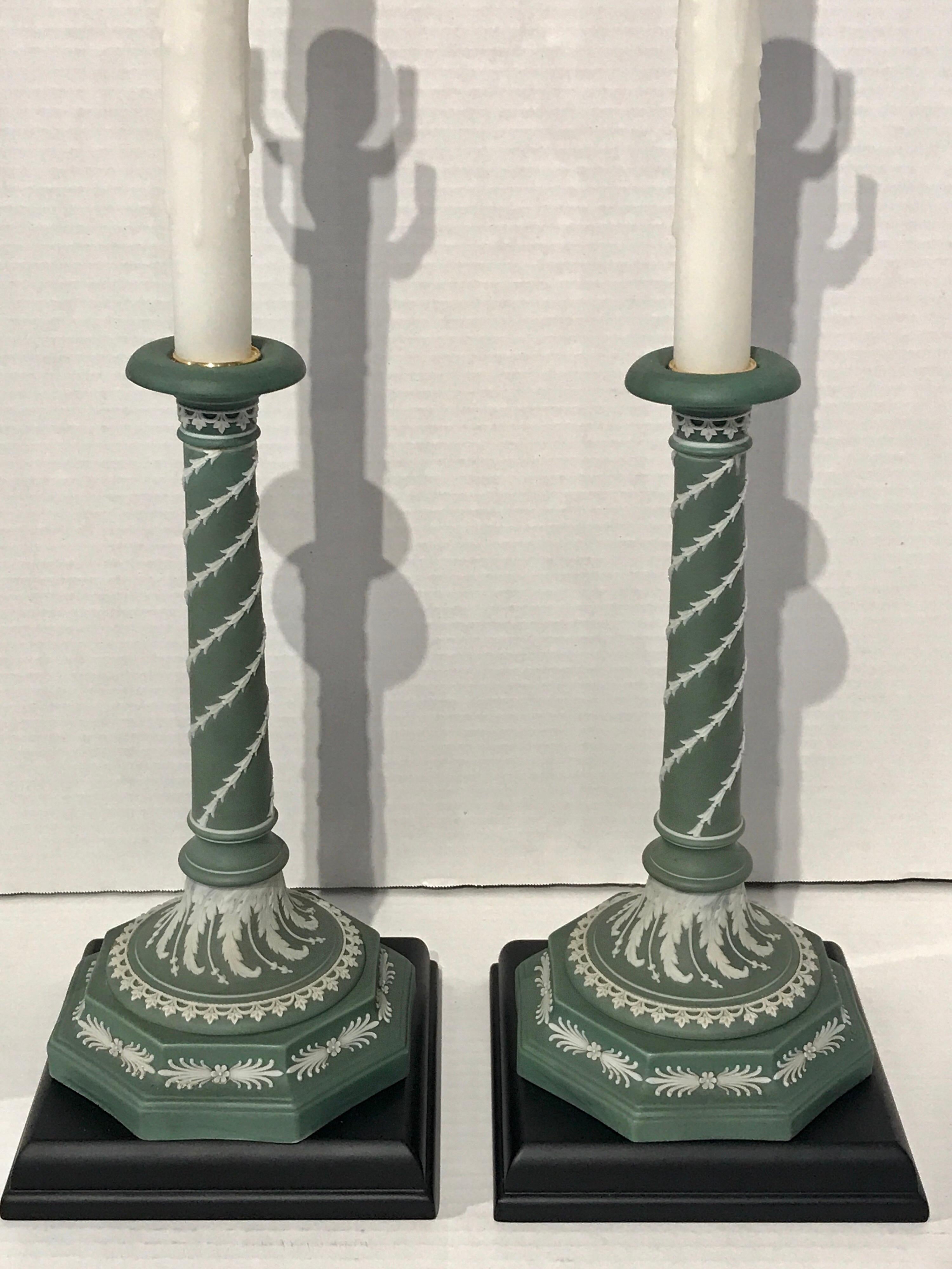 Pair of olive green and white Wedgwood candlesticks, now as lamps, Each one mounted on a ebonized wood base. The candlesticks alone are 5.5