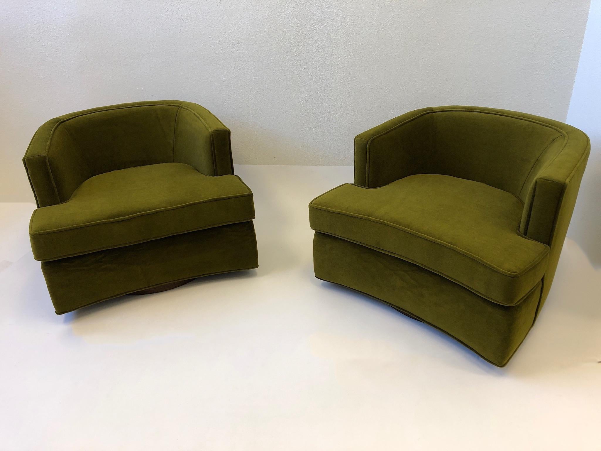 A spectacular pair of swivel lounge chairs designed by Harvey Probber in the 1950s. The chairs have been newly recovered in a beautiful olive green mohair fabric. The base is dark brown stained oakwood. One of the chairs retains the Probber label