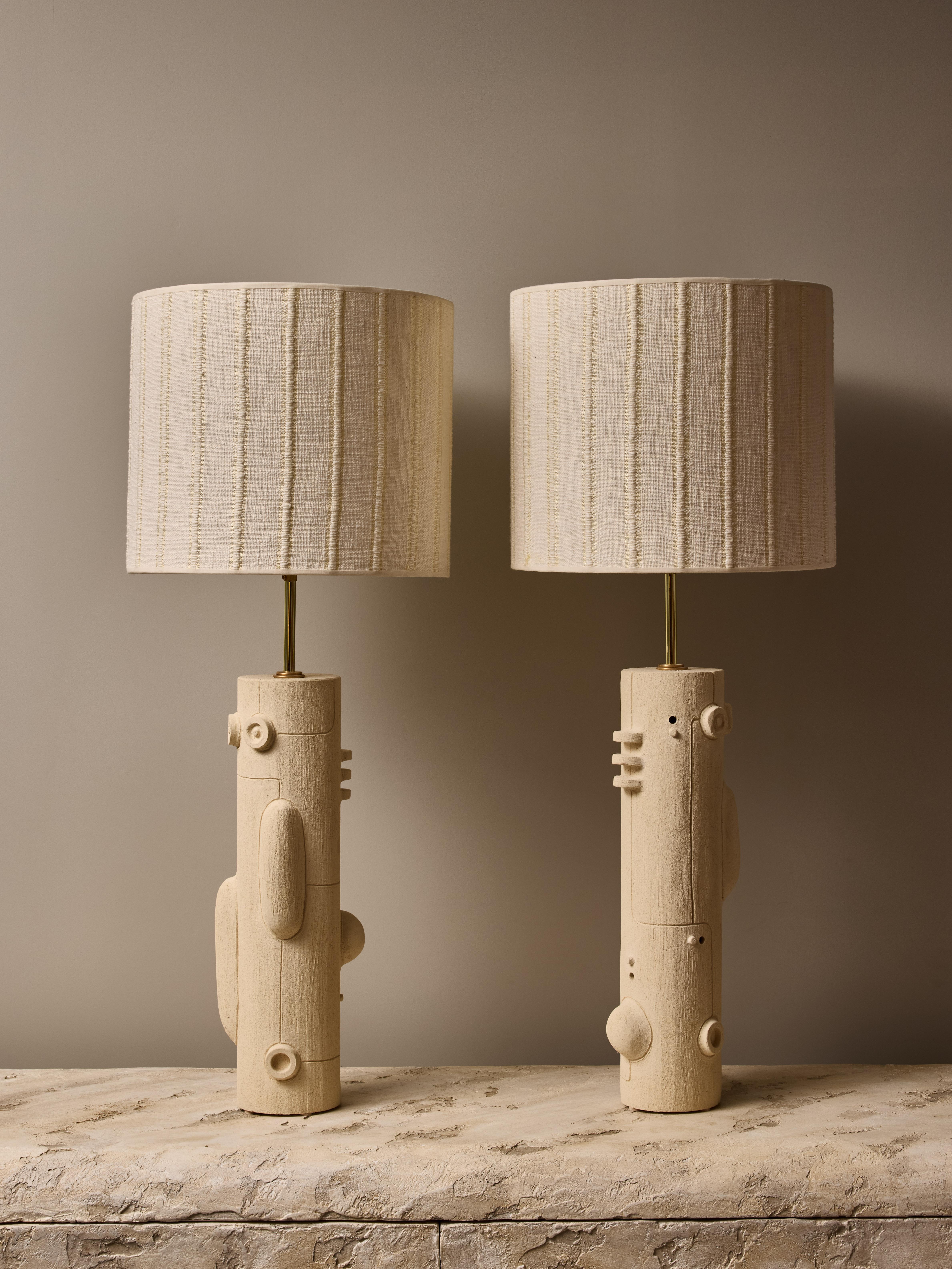 Pair of ceramic table lamps by the talented french contemporary artist Olivia Cognet.

These thin tubular shape lamps have mirrored maze design with soft geometrical shapes and thin lines, brass hardware and topped with a custom lampshade.

Stamped