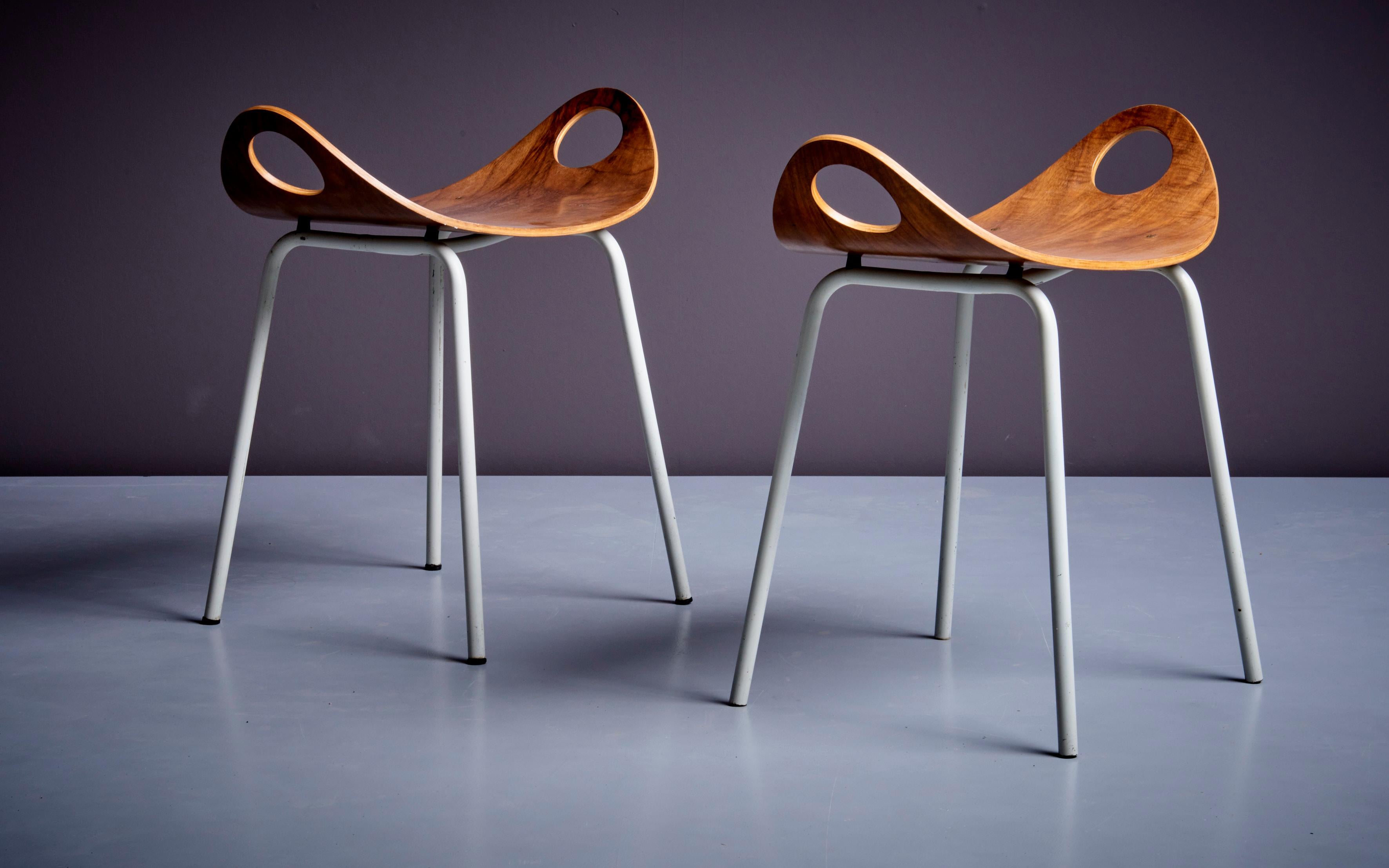 The stools are made of four white metal legs and a walnut plywood seat which curves upwards. A simple and elegant design, labelled by J. Merivaara. Authentic patina.