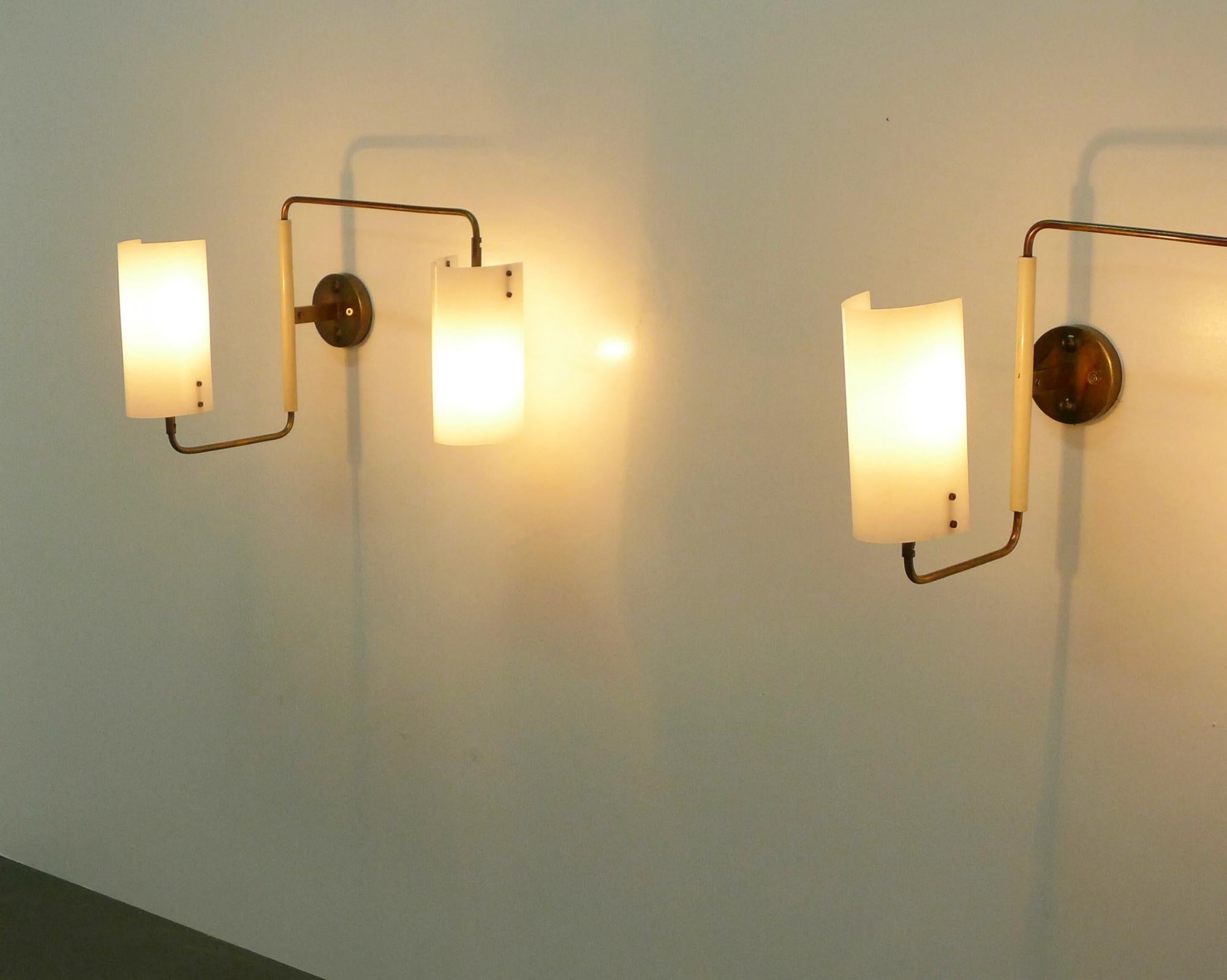 A rare pair of twin-light adjustable wall lights, designed in 1955 by Tito Agnoli and manufactured in the 1950s by Oluce.

The white opal perspex shades can be turned slightly to adjust the lighting as required and sit on articulated brass arms of