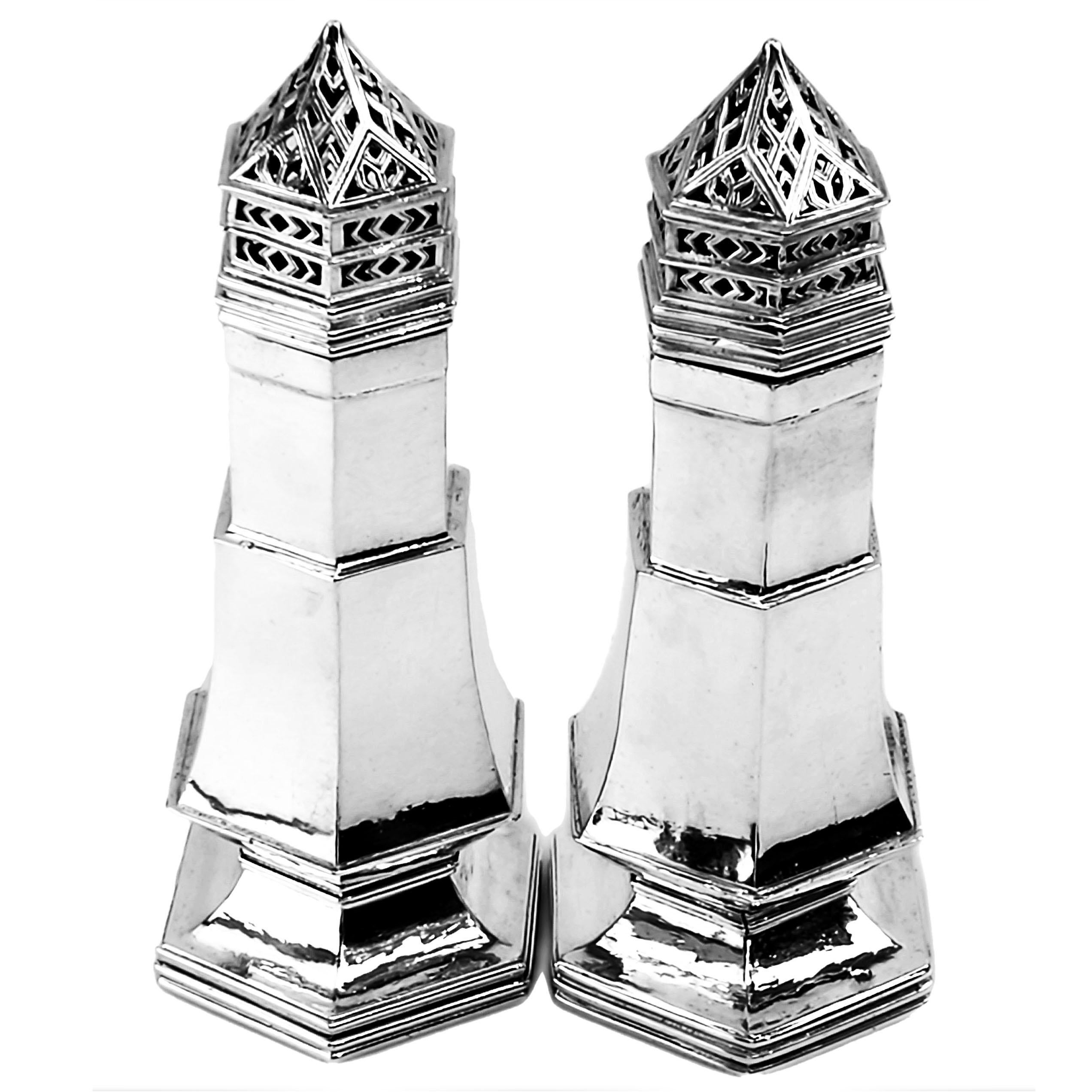 A pair of Arts & Crafts sterling silver sugar casters by the esteemed Silversmith Omar Ramsden. These Sugar Shakers have a tapered hexagonal shape and stand on spread pedestal feet. The exterior of the Casters have a lightly hammered finish. The