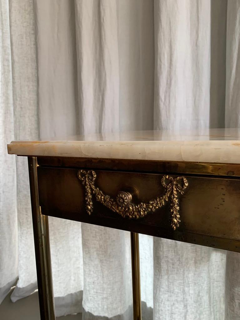 Beautiful pair of antique French bed side tables or nightstands with a brass base and with vivant colorful onyx table tops. One table comes with a lower shelf and one with a small cabinet with at door also in onyx. Both tables comes with a small