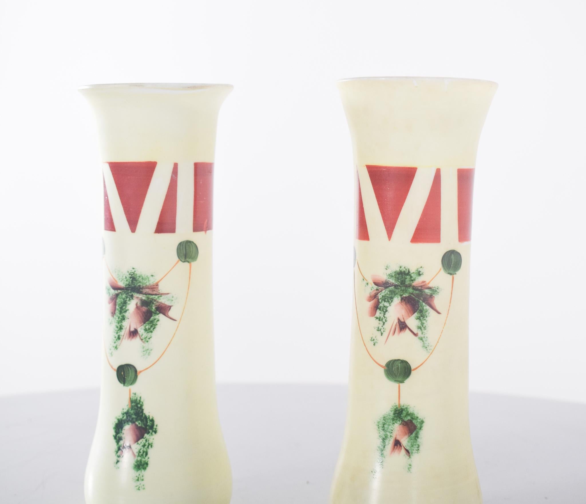 Paire de cruches en verre opalescent. Décoration polychrome, forme cylindrique, base et embouchure légèrement effilées. Ils présentent un design élégant et délicat, avec des couleurs douces, principalement l'ivoire. Le décor combine des éléments