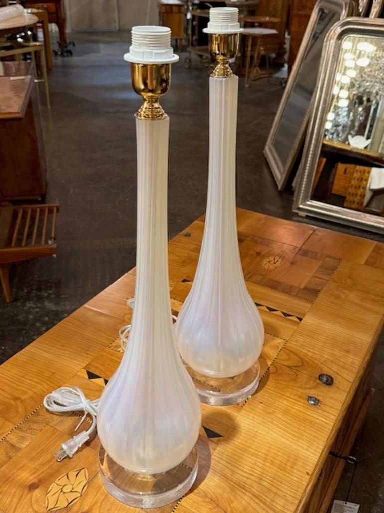 The product is a pair of Murano glass lamps that feature an opalescent glass and a vase formdesign, giving them a unique and elegant appearance. These lamps are sure to add a touch of sophistication to any room, making them a perfect addition to a