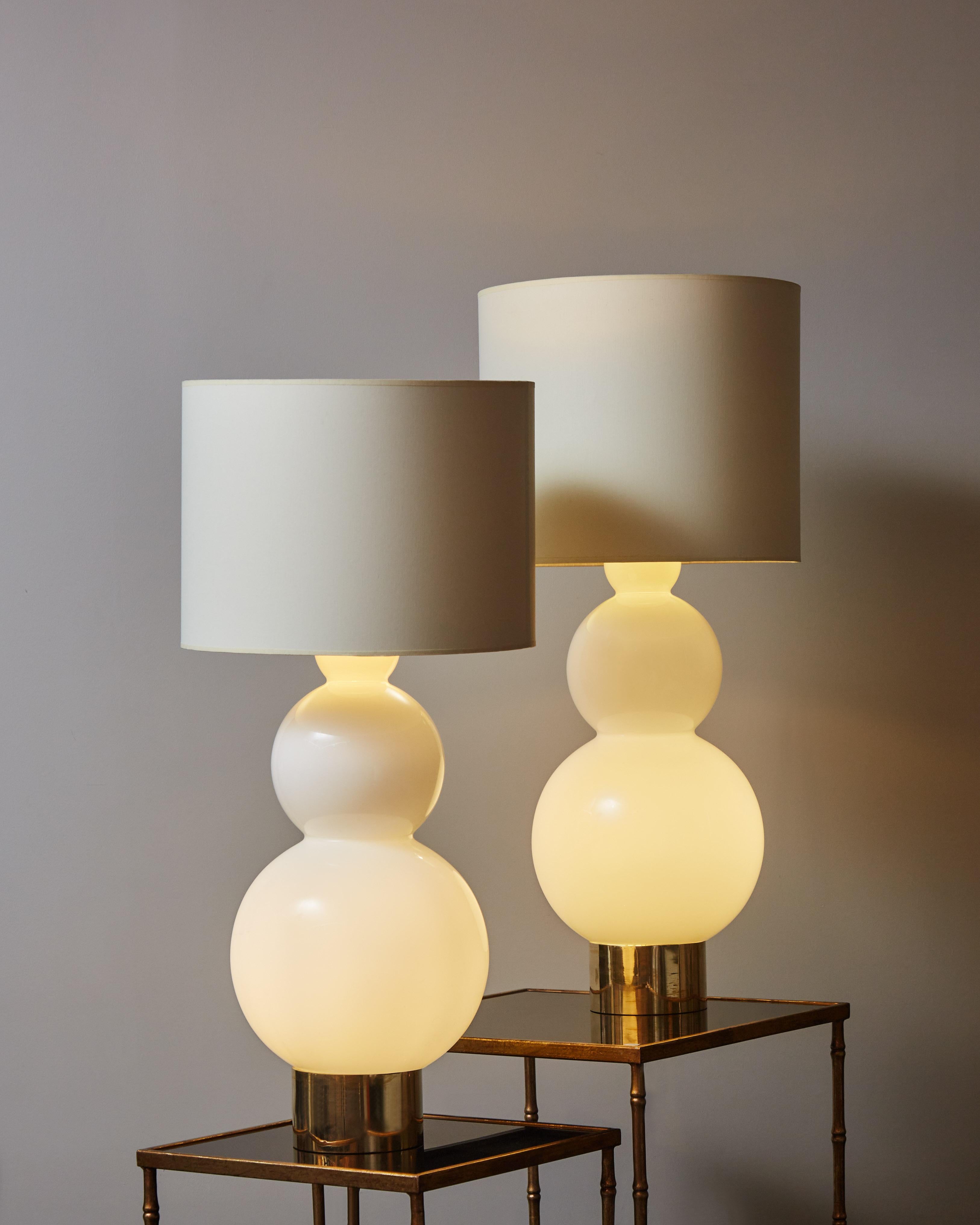 Pair of bubbly table lamps made of a single opaline glass piece with brass feet. Two lightbulbs inside the body of each lamp provide a smooth lighting in addition to the regular top bulb.