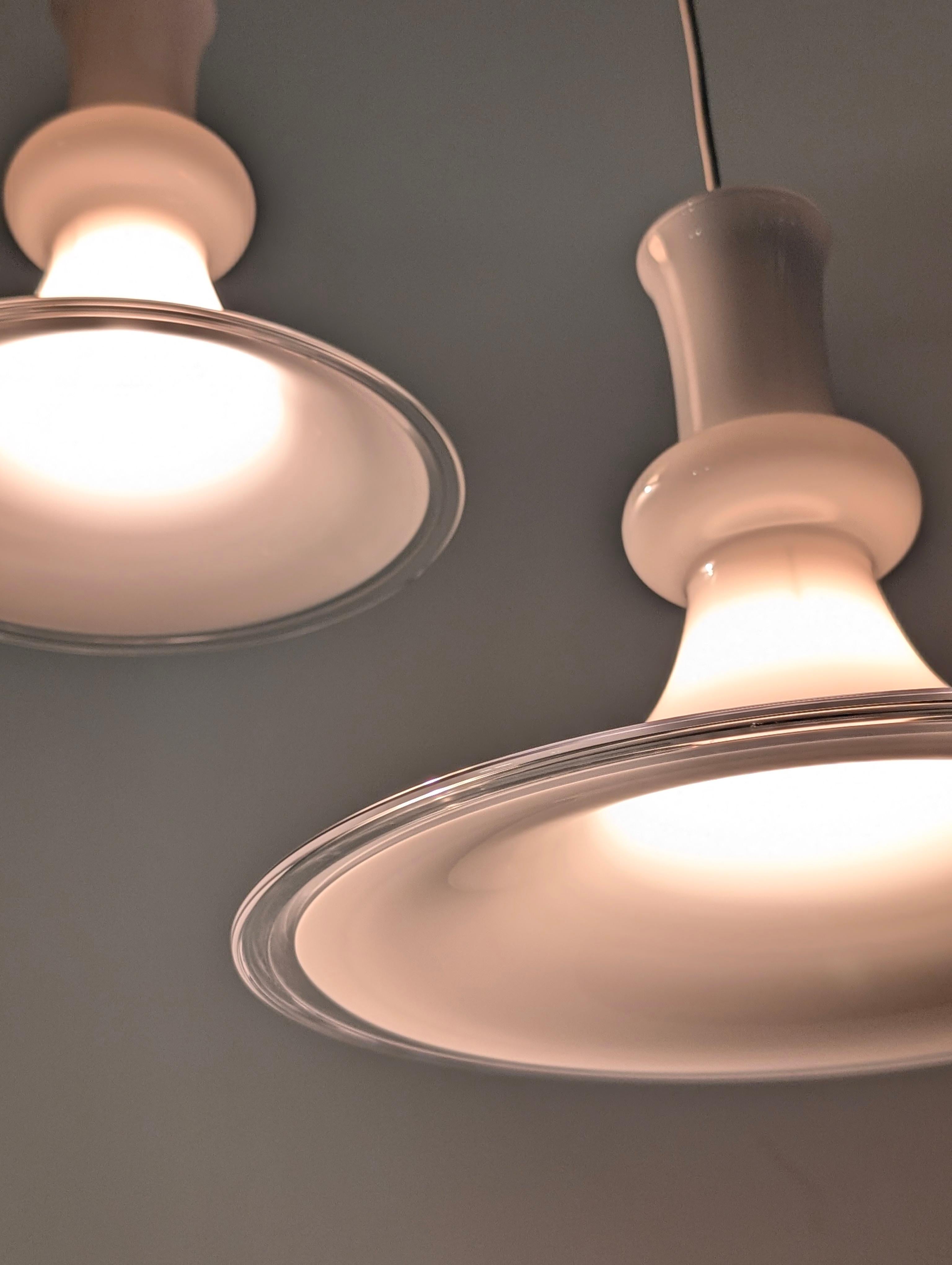 Elegant pair of pendant lamps designed by Michael Bang for Royal Copenhagen and produced by Holmegaard in the 1970s, a collaboration that embodies the delicacy of Scandinavian design and the excellence of Danish glassmaking. Made of glossy white