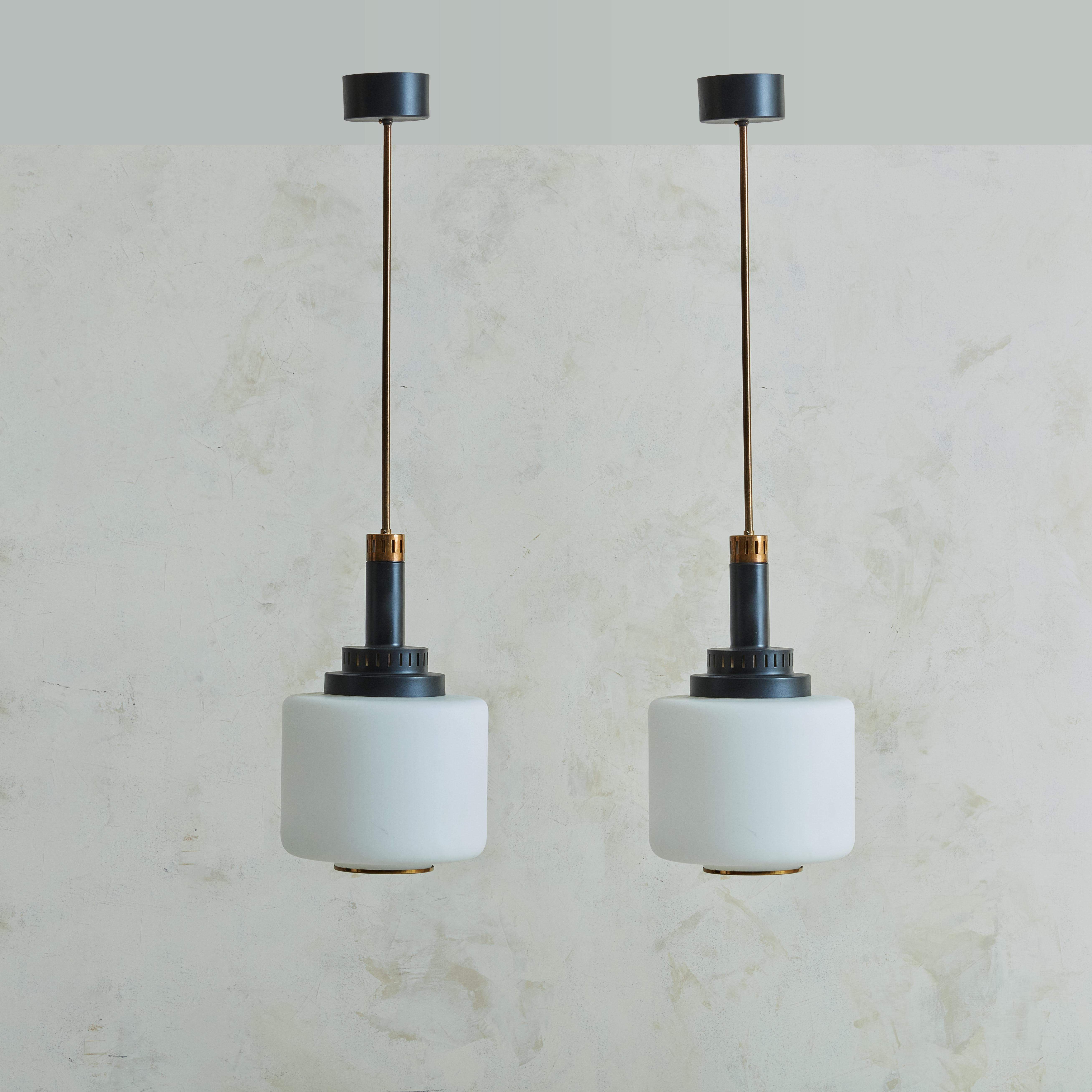 A pair of 1960s pendant lights by Stilnovo. This pair of beauties made by the combination of brass, lacquered metal and opaline glass are a perfect example of the mid-century productions this famous brand did in collaboration with many famous