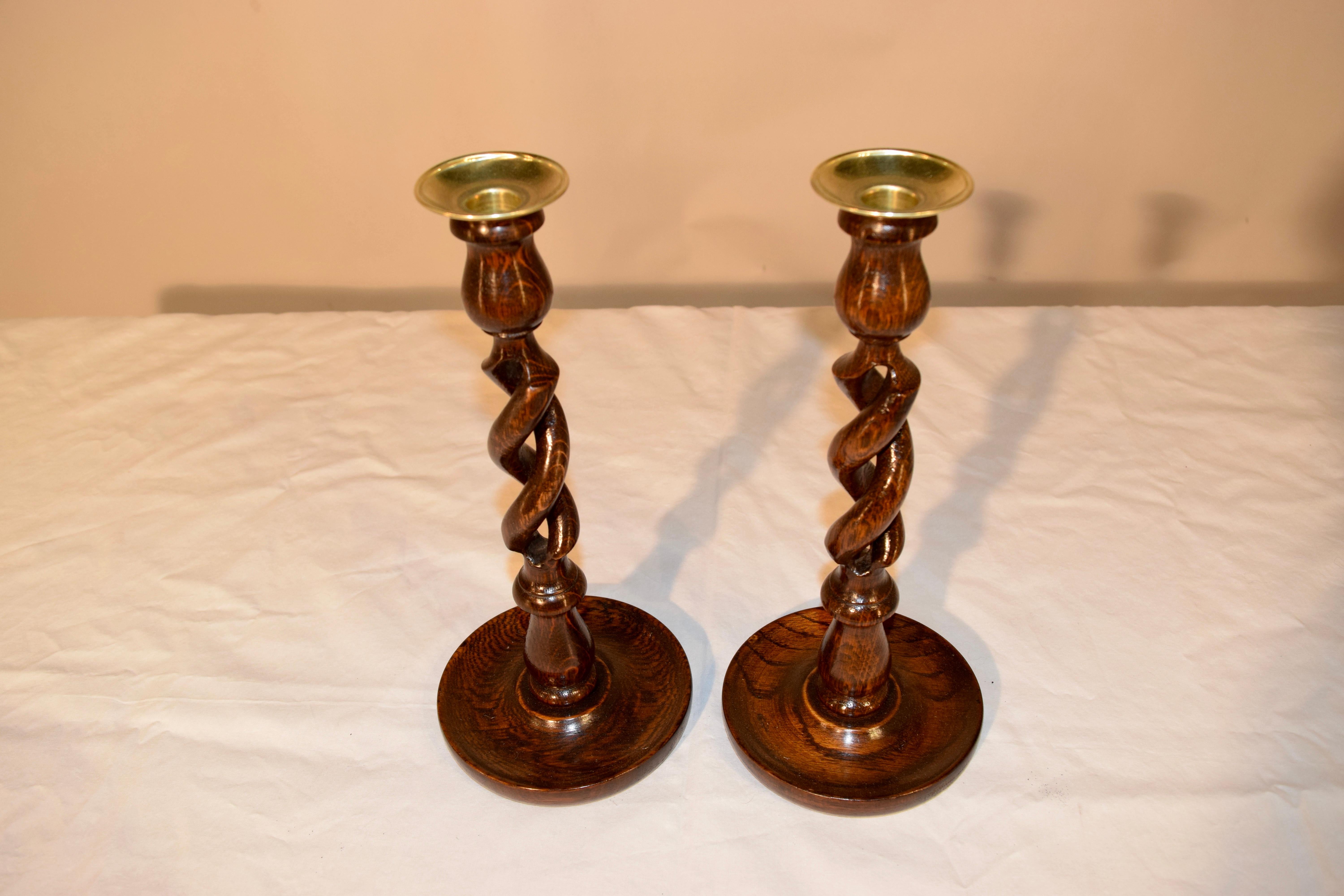 Pair of 19th century English oak candlesticks with open barley twist stems resting on hand-turned dish shaped bases and topped with hand cast brass candle cups.