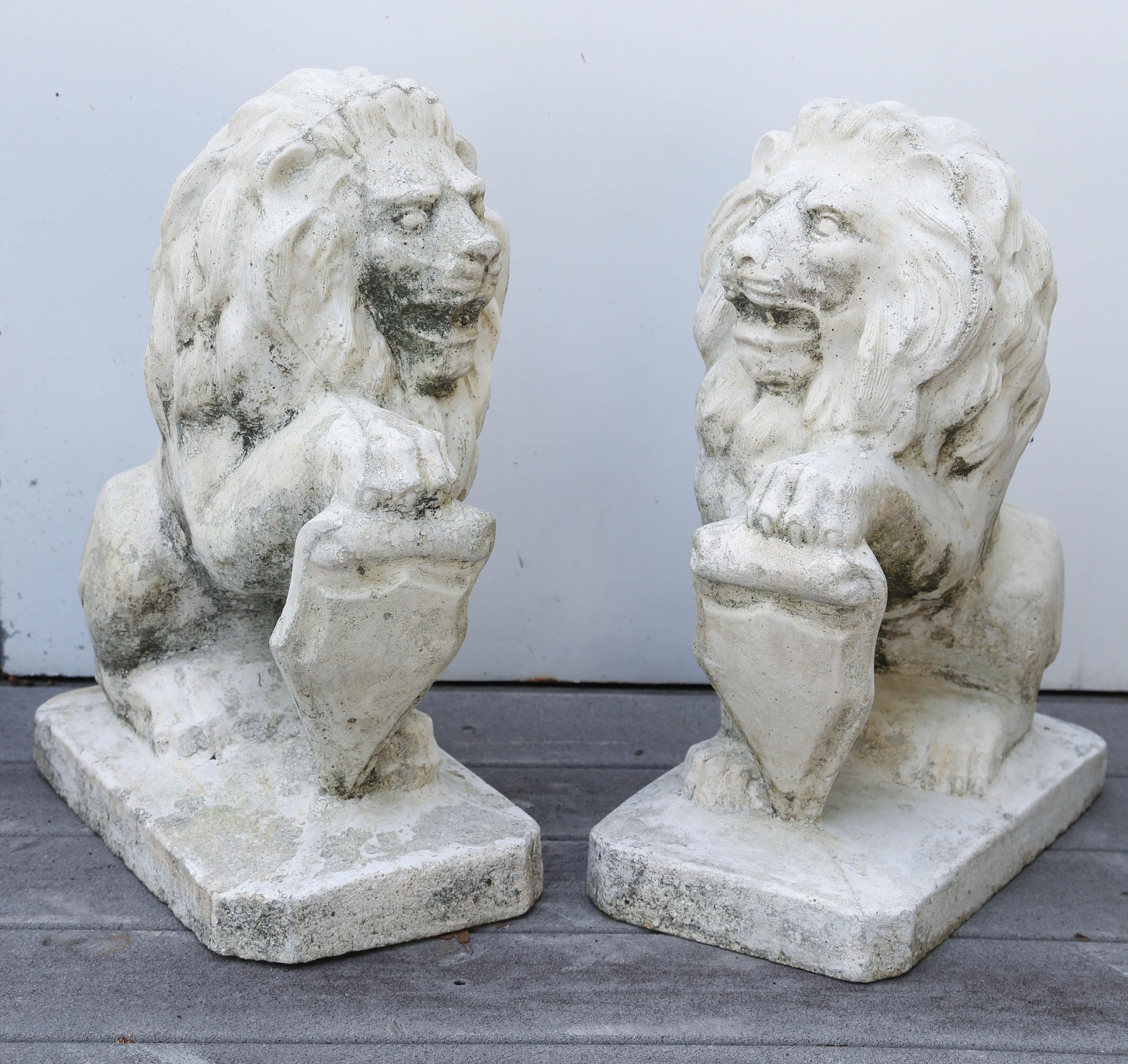 Vintage pair of French cast stone opposing lions with crests.