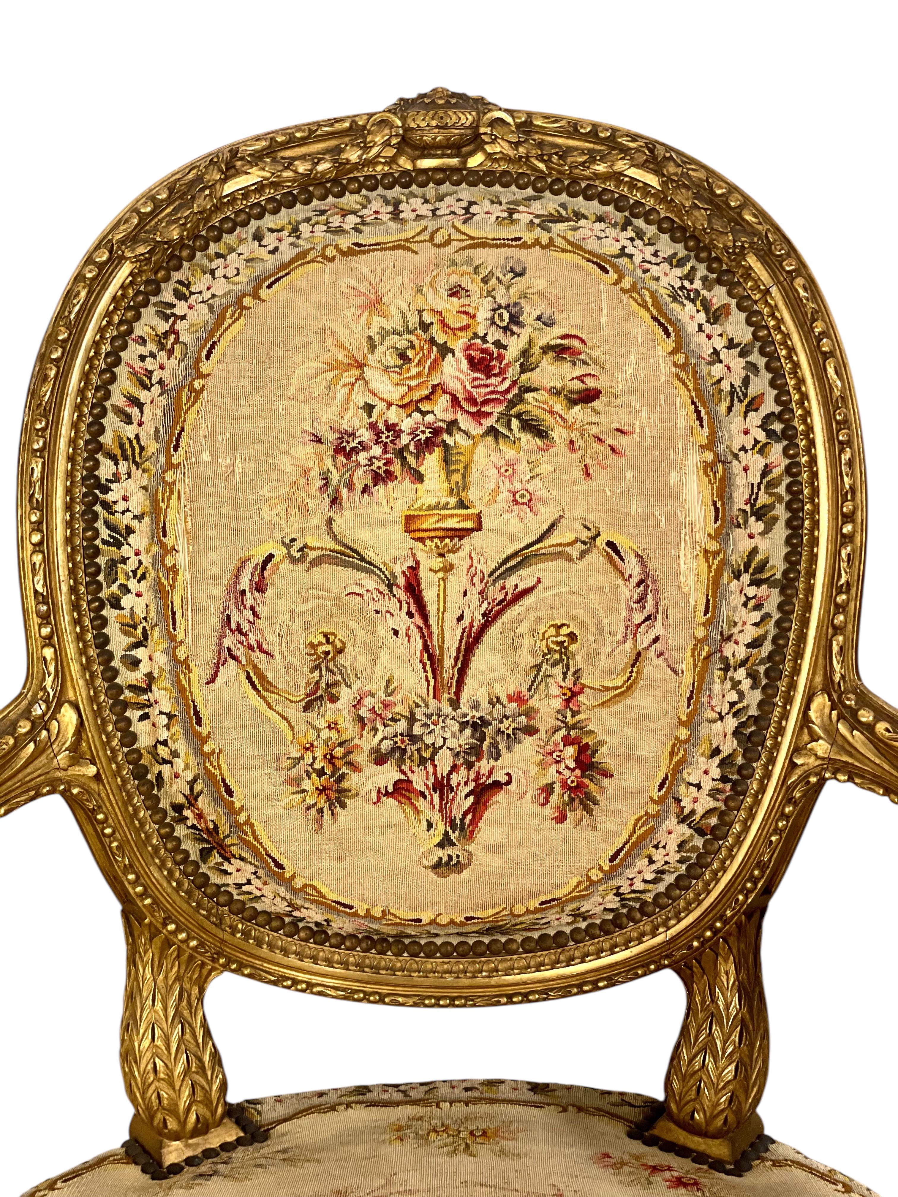 Exquisita pareja de sillones de madera dorada de estilo Luis XVI con fundas originales de tapiz de Aubusson en tonos dorados. Elegantemente tallado y tapizado, este fino conjunto exhibe motivos ricamente tallados por todas partes, así como una