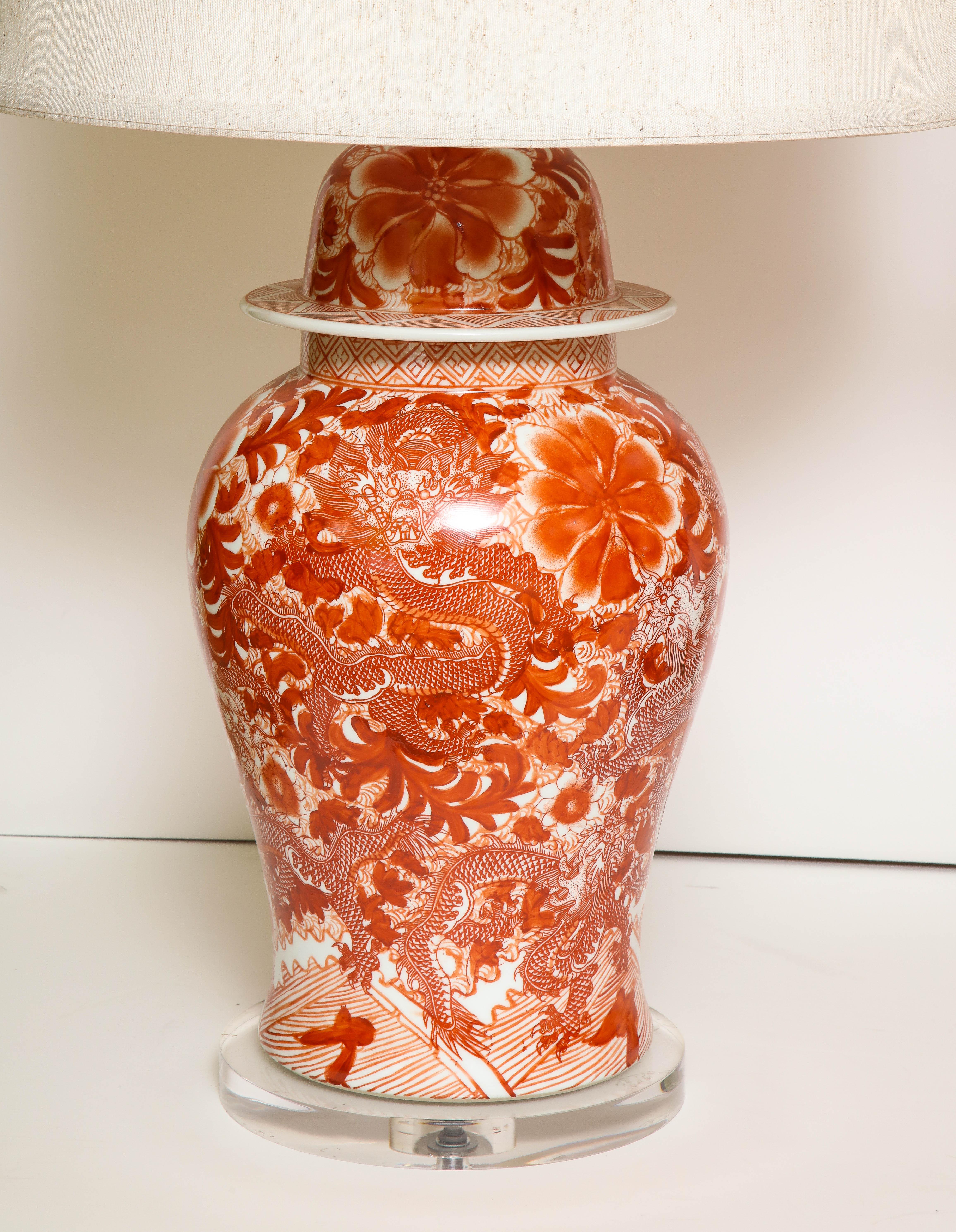 A pair of orange and white Chinese ceramic jars, converted to lamps, with linen shades and a Lucite base. A great (and useful) way to add color to a room.