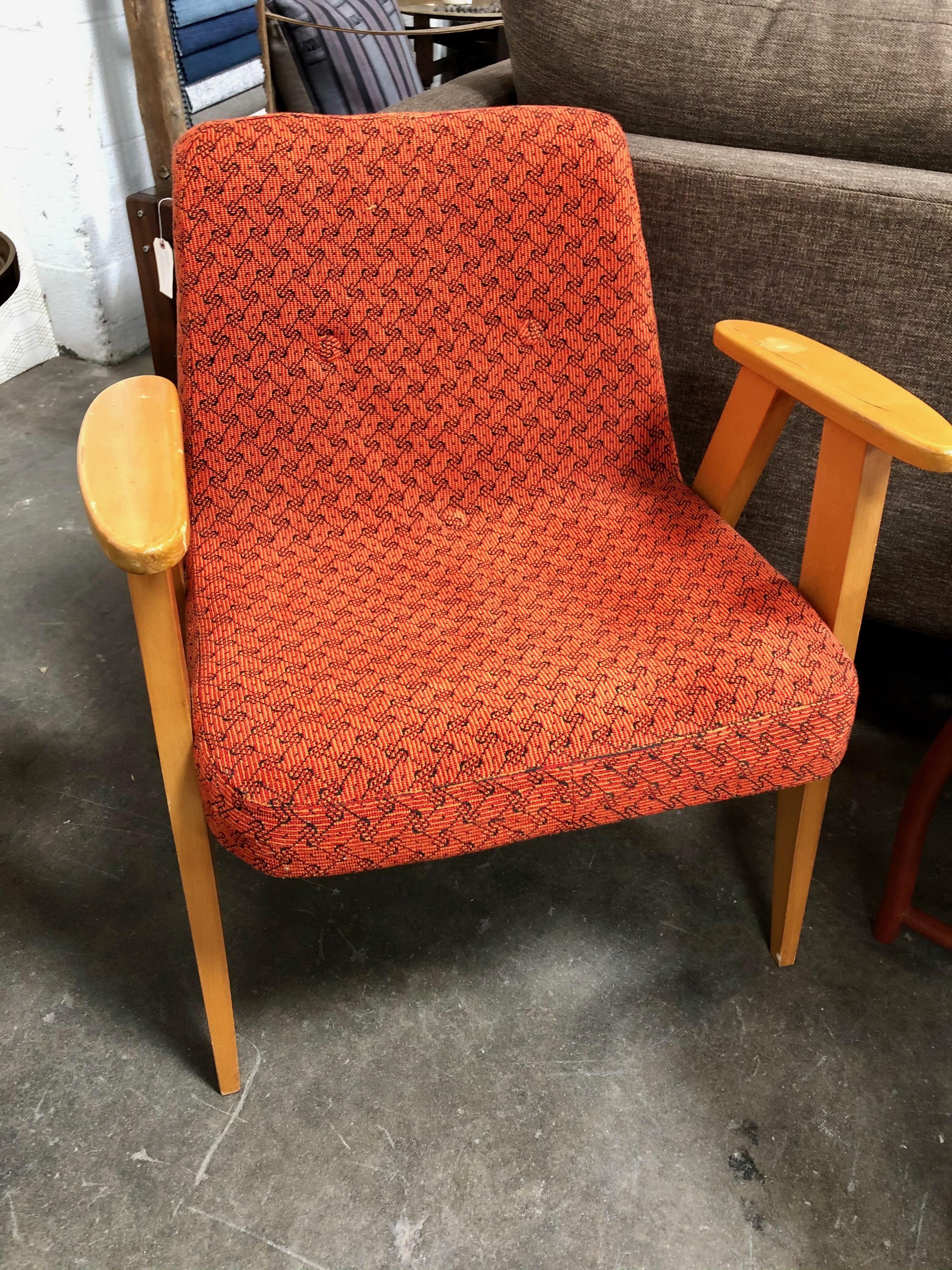 A pair of Mid Century armchairs in a bright orange red color.