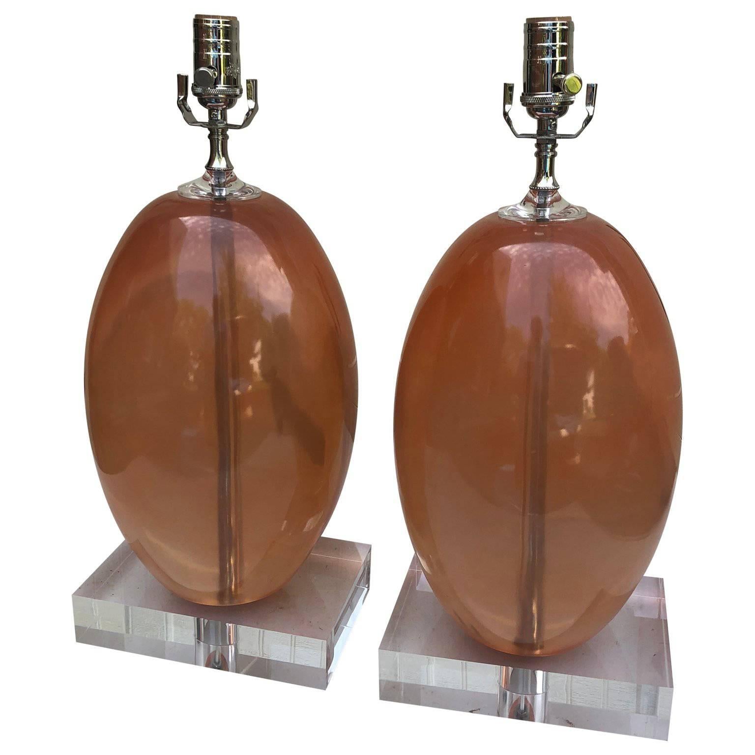 Paar schwere orangefarbene ellipsenförmige Tischlampen aus Harz auf dickem Lucite-Sockel.

             