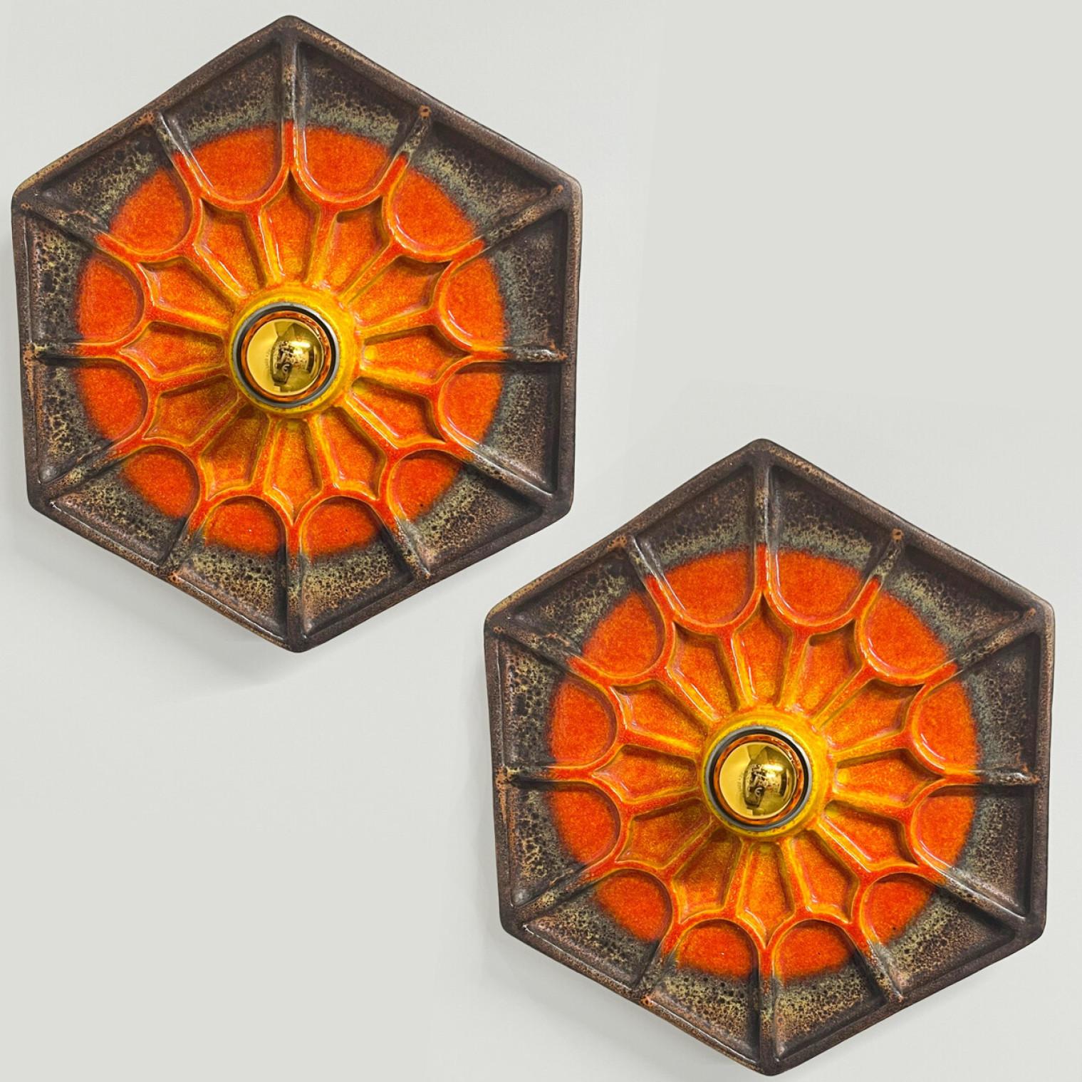 Pair of Orange hex-shaped ceramic wall lights. Manufactured in Germany in the 1970s. The base of the light is hexagonal and there is a beautiful ceramic web on top of that.

The fixtures can also by used as flush mount.

The style of the glaze is