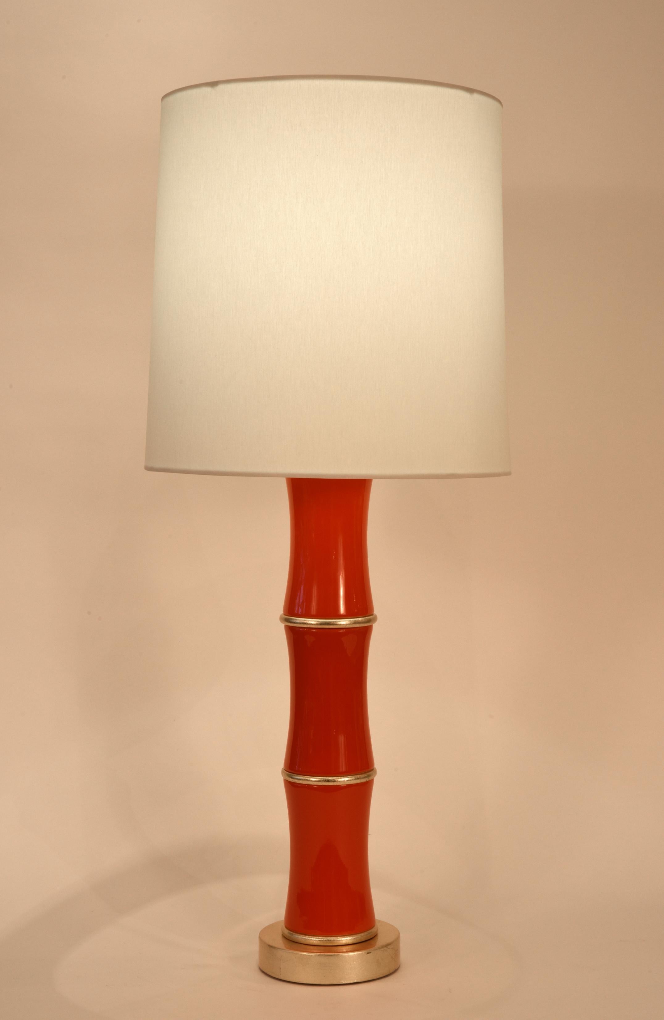 Pair orange porcelain task or table lamp with gold leaf wood base. Each lamp is in excellent condition, rewired for US use. Each lamps come with a round drum shade with silk exterior. Each measure shade measure 13 inches x 13.5 inches x 14 inches.