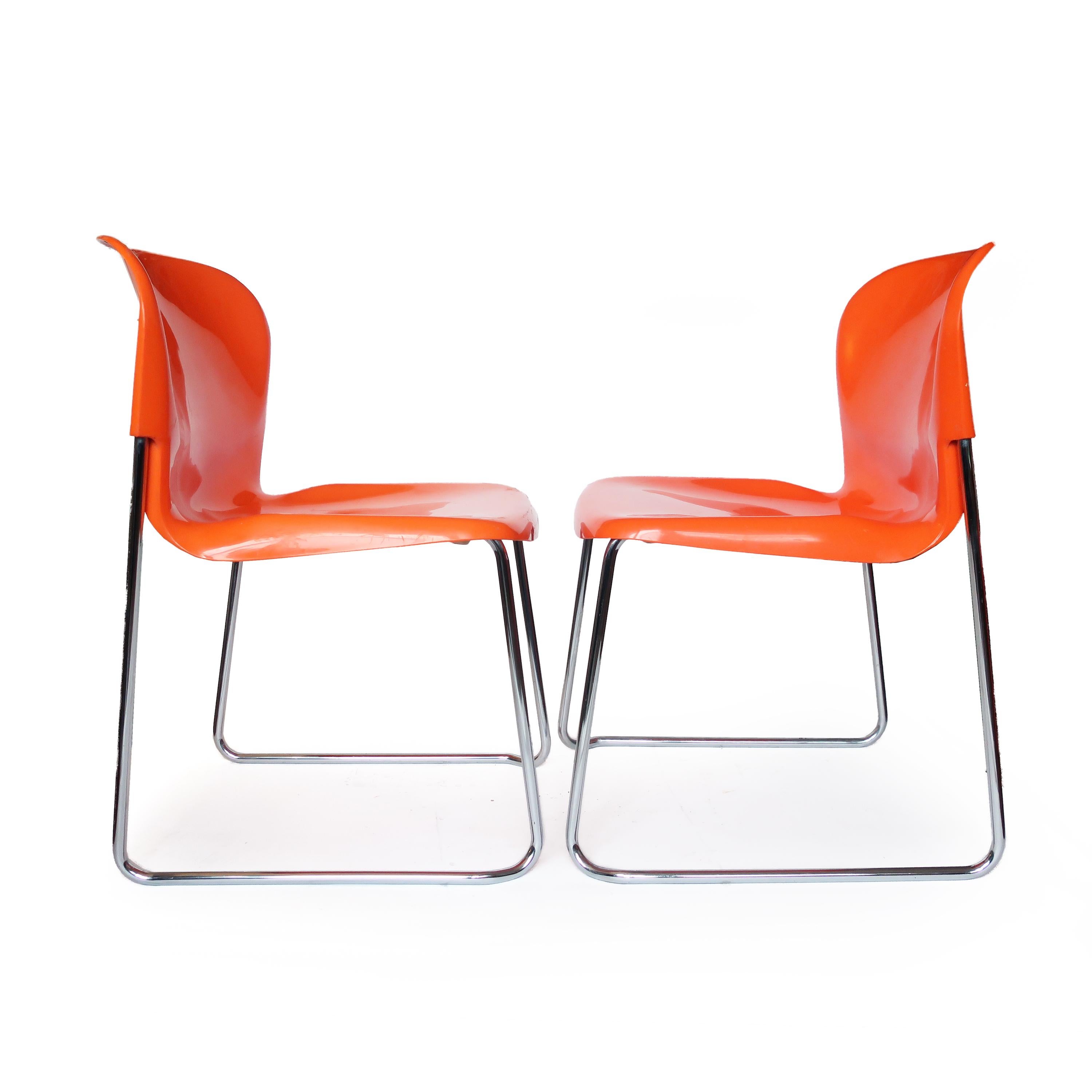 A brightly colored pair of SM 400 Swing chairs designed in the 1970s by Gerd Lange for Drabert, a West German furniture maker. Orange molded plastic seats sit on a chrome frame that allows for easy stacking for storage. In good vintage condition