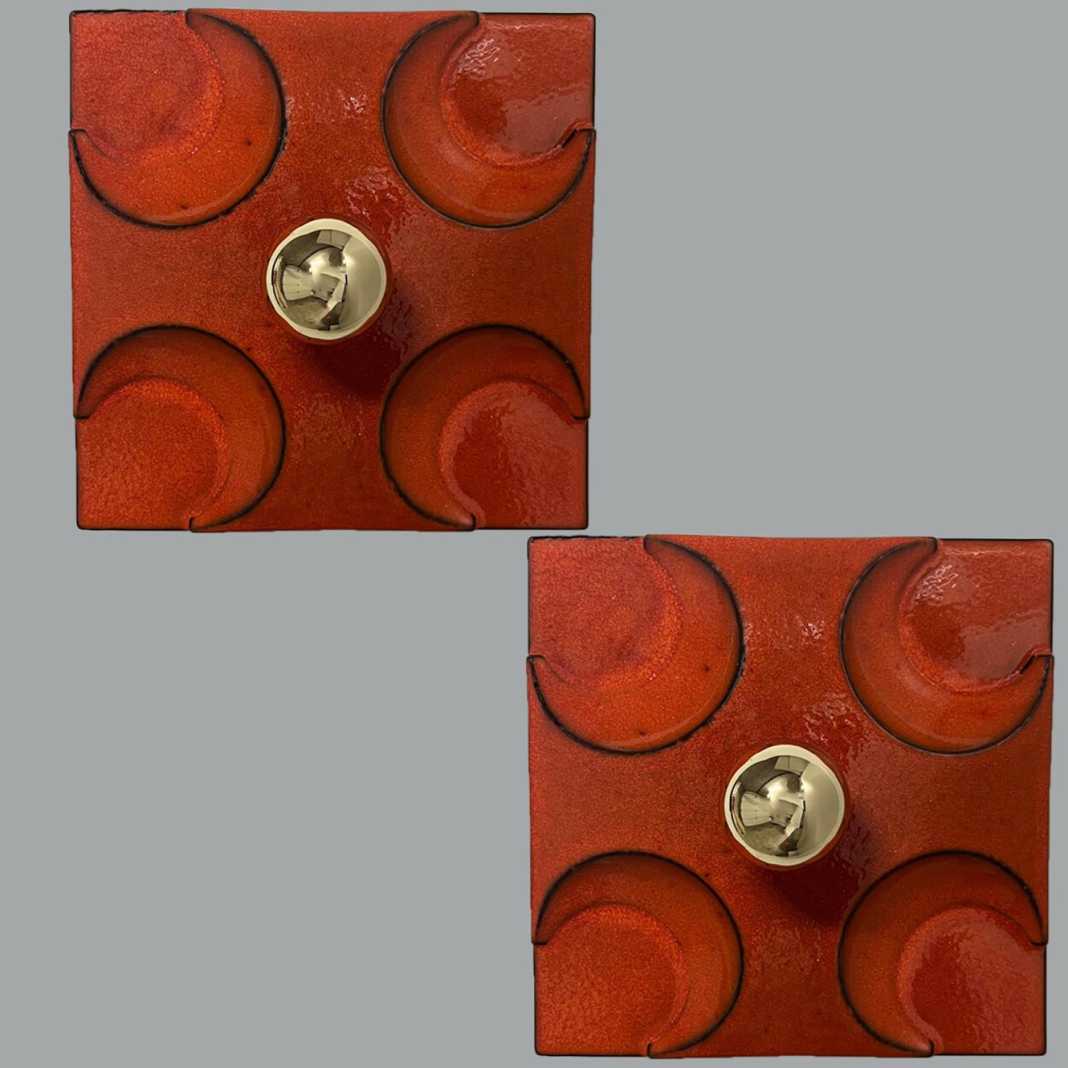 Pair of Orange square-shaped ceramic wall lights/flush mounts in Fat Lava style. in Germany in the 1970s. The base of the light is square and there is a beautiful ceramic cross on top of that.

This lights have a unusual shape. This makes it