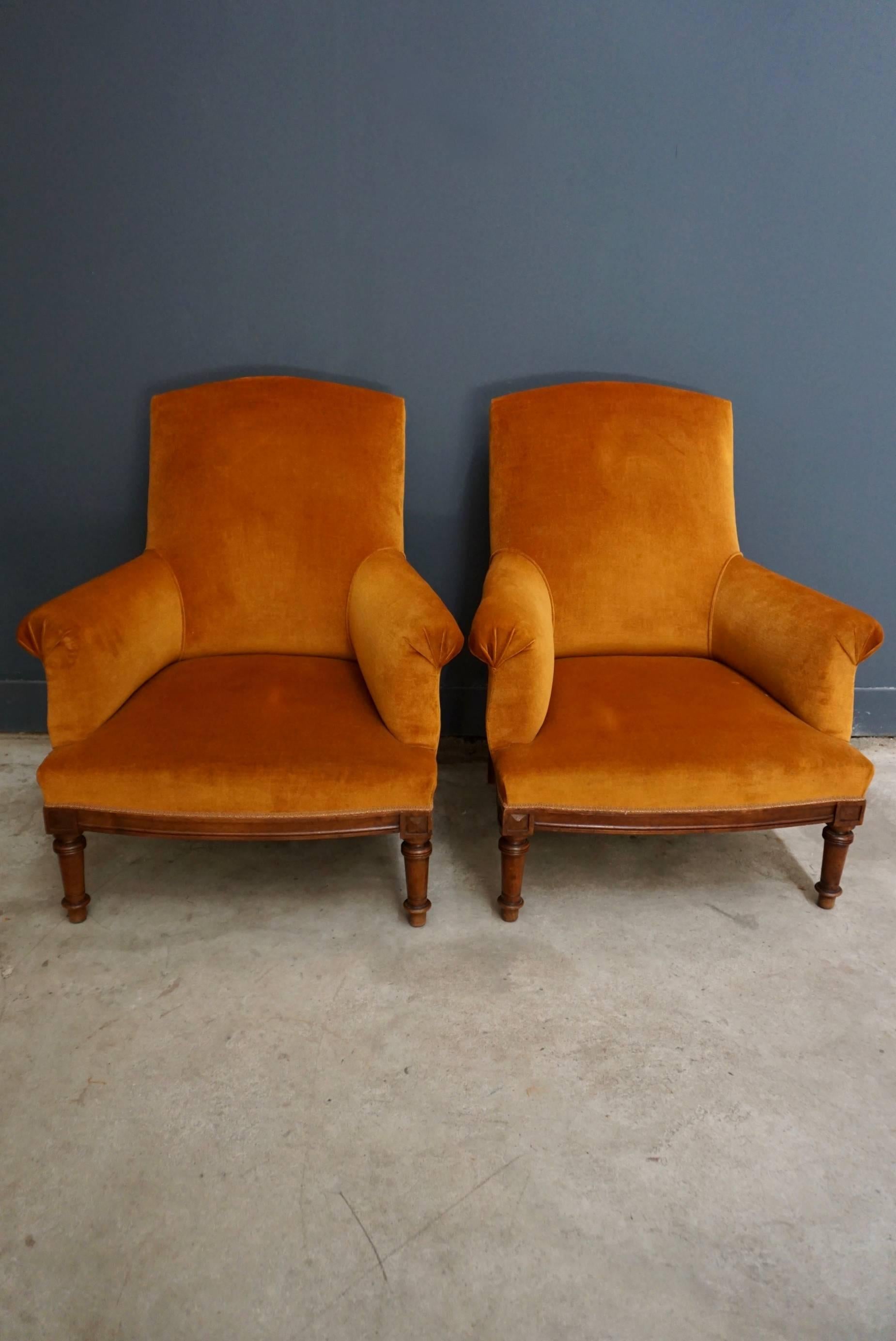 This pair of French velvet chairs were designed and made around the 1920-1930s in France. They feature a solid walnut base and a frame upholstered in most likely the original orange velvet. They are in a very good condition for their age and very