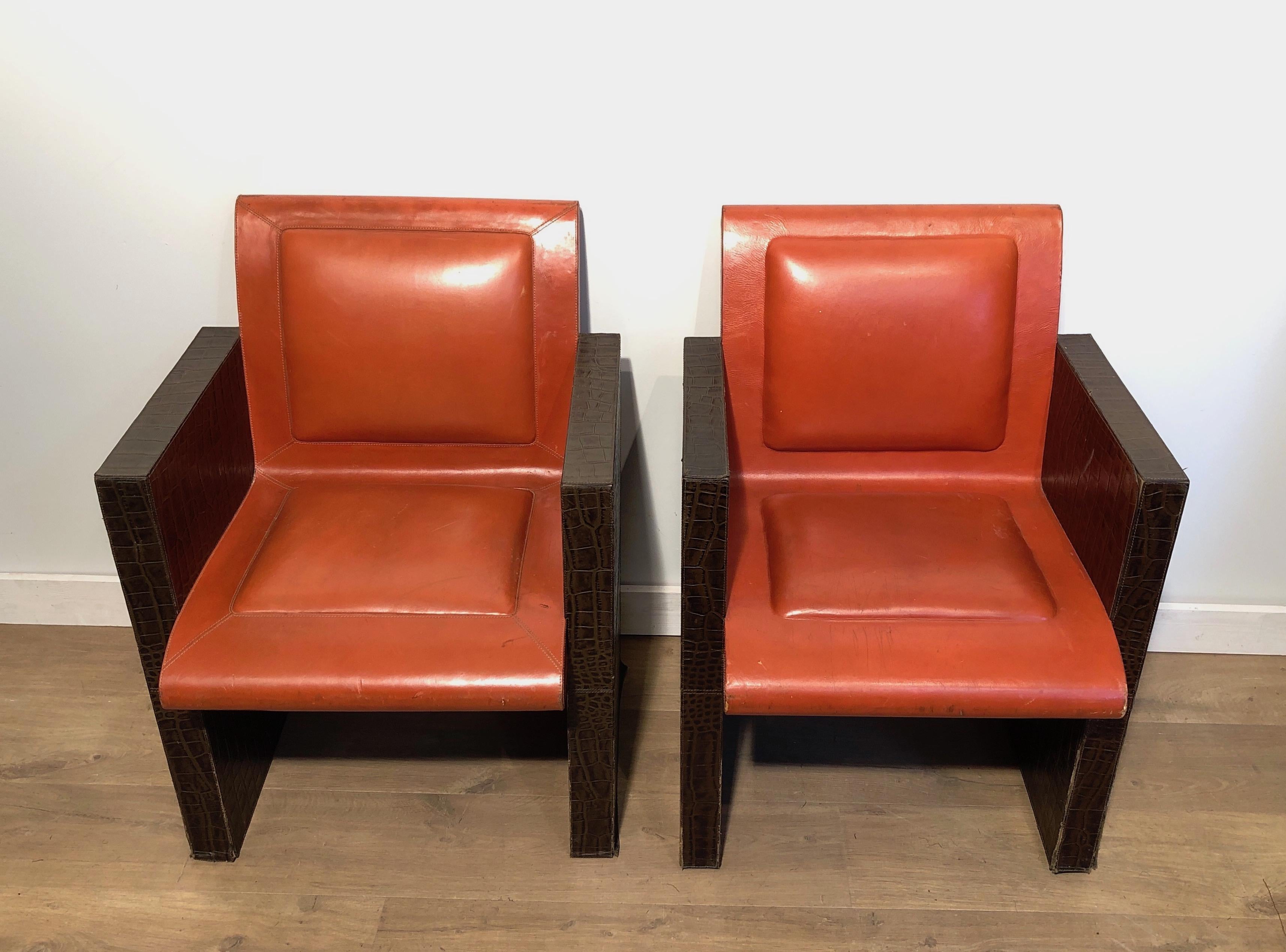 This very unusual pair of armchairs is made of an orangeish and brown leather. The armchairs can be sold individually in we have 3 of these available. This is a French work. Circa 1970