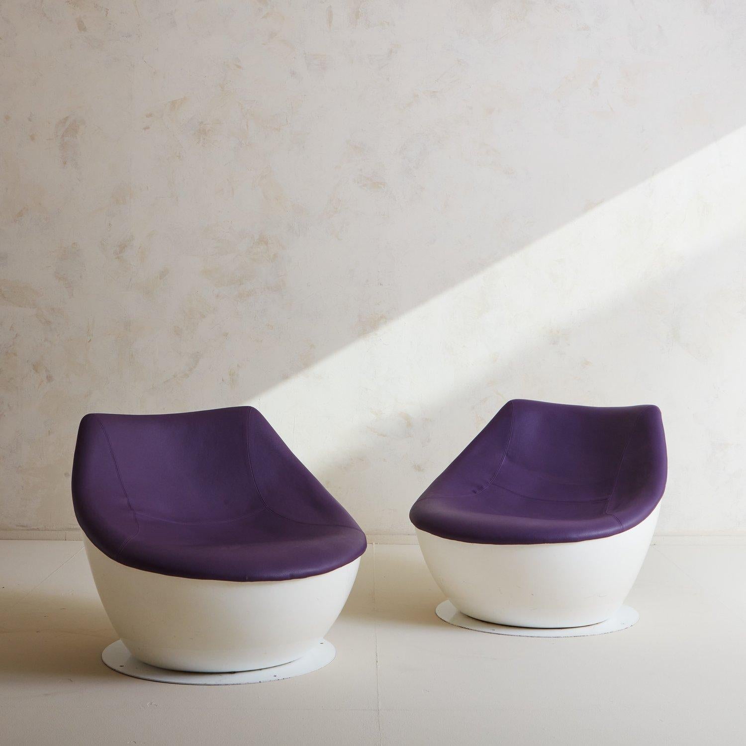 A pair of Orbital chairs designed by Christophe Pillet for Modus in 2008. These striking chairs feature rounded white fiberglass frames and retain their original purple vegan-leather upholstery. They stand on white circular aluminum bases. Imprinted