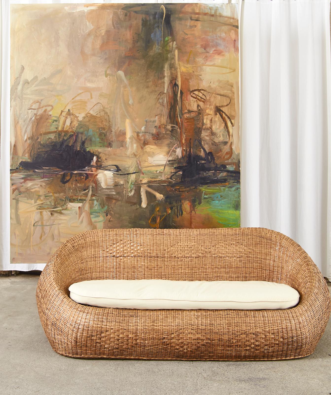 Fantastic oversized, bulbous form sofa settees featuring rattan frames covered with woven wicker. The  modern designs of the sofas touch on biomorphism, while being grounded in natural organic materials. The matching pair have a subtle geometric