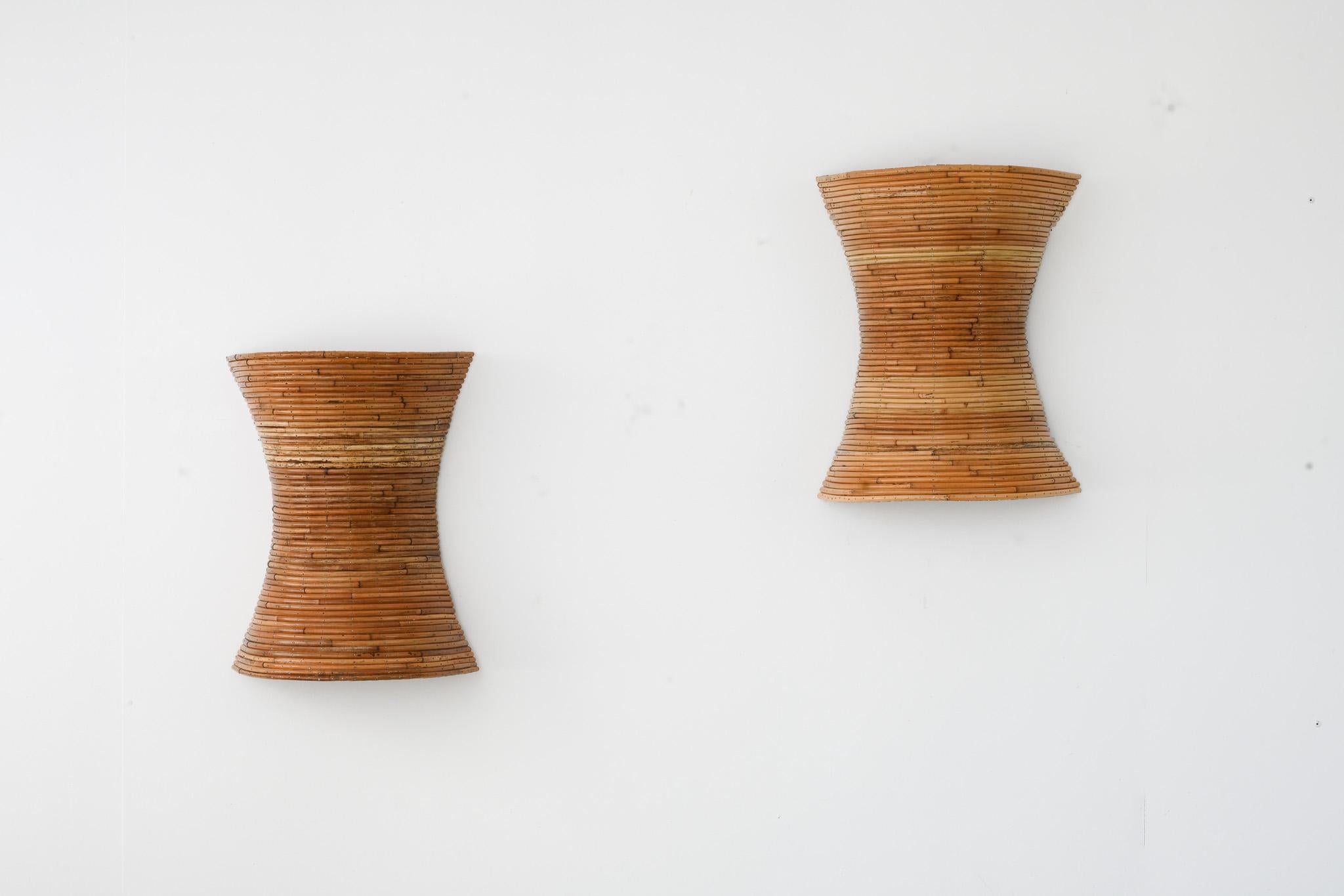 Queste splendide applique in rattan fatte a mano sono pezzi unici e artigianali, realizzati meticolosamente con rattan completamente naturale e proveniente da fonti sostenibili. Ogni applique presenta una sorprendente silhouette a clessidra, formata