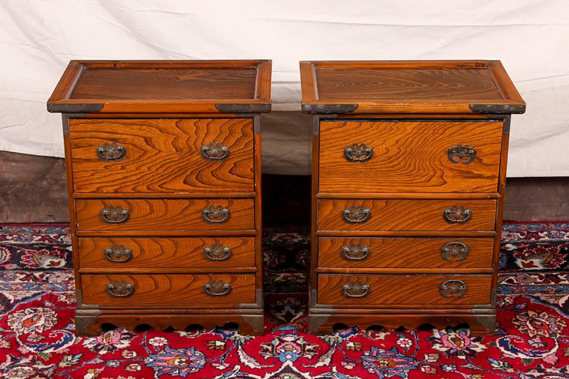 Pair of oriental exotic wood bedside chests, banded tops in relief, one long over three short drawers, the middle two with compartments, and all lined in red felt, shaped lower frames with block feet, metal hardware on the corners and insect form