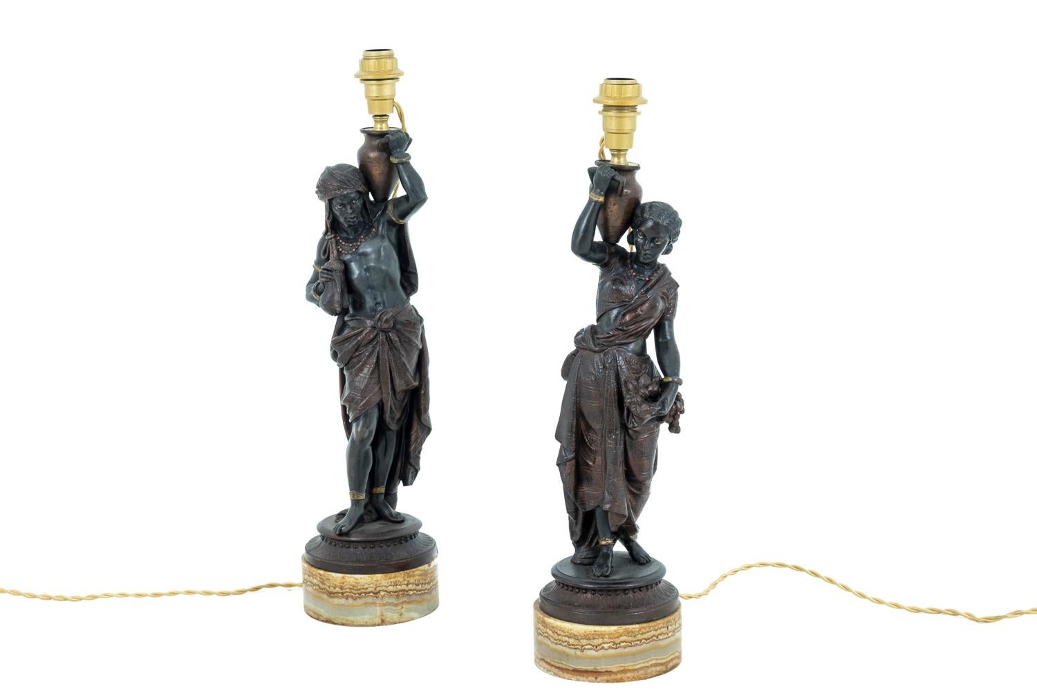Pair of Oriental style lamps in spelter figuring: for one, an African man wearing a fabric wrapped around his head and falling on his back and a fabric wrapped around his hips. For the other one, an African woman wearing a small top, a sarouel and a