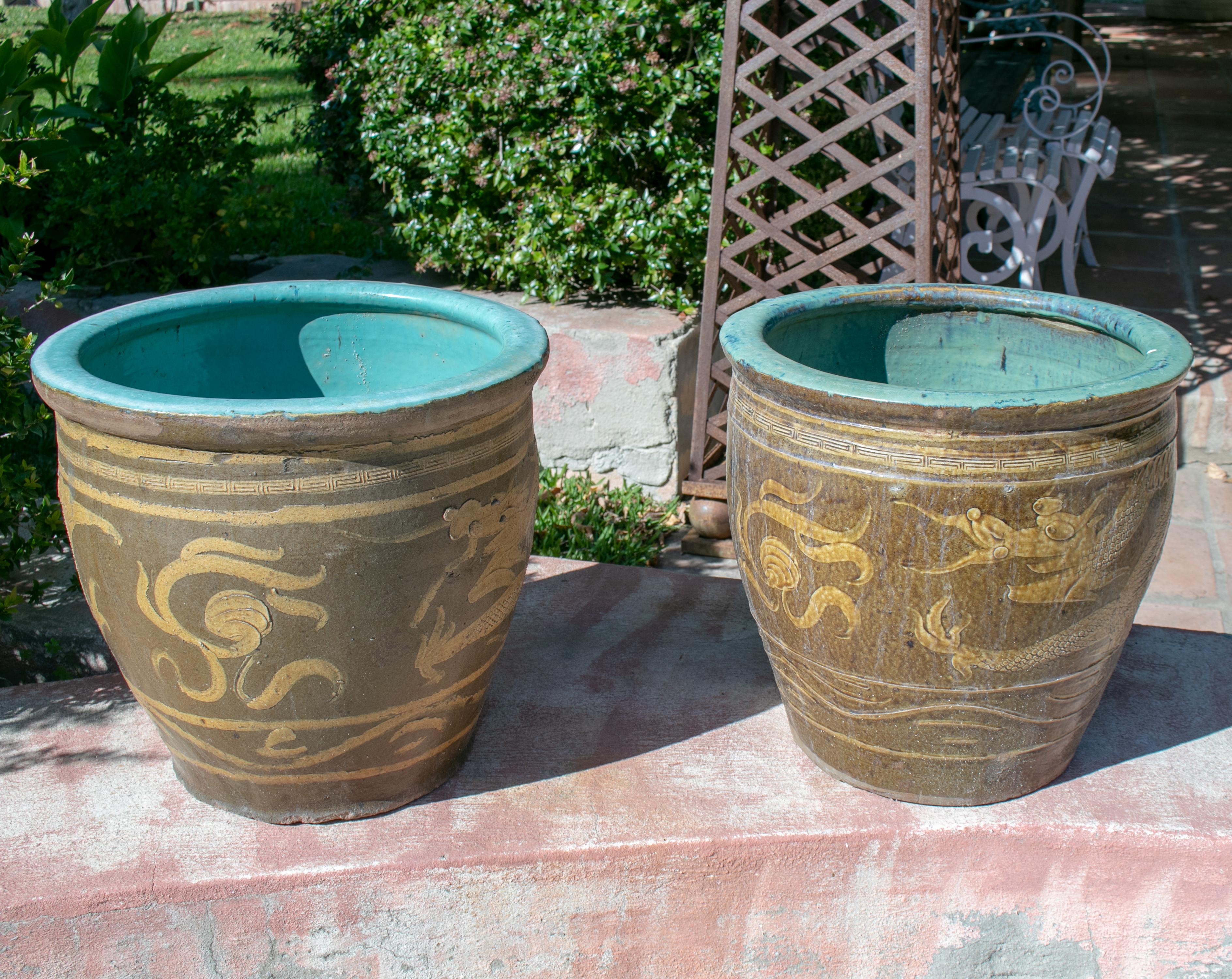 Pair of oriental style ochre colored pots with dragon decoration.