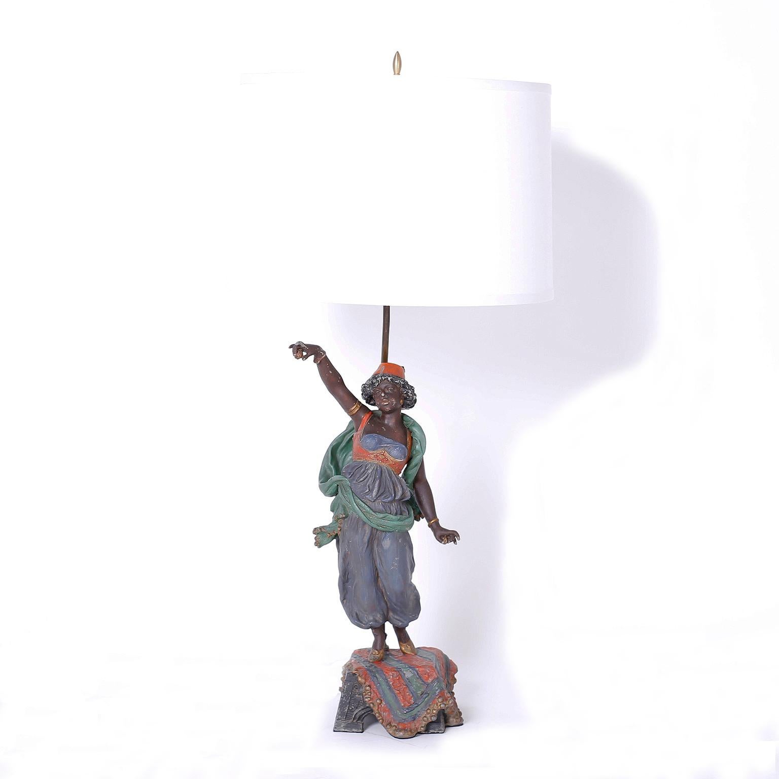 Pair of antique table lamps crafted in painted cast metal, depicting male and female Moroccan figures, a dancer, and a musician both dressed in exotic native garb and standing on a pedestal with carpets.